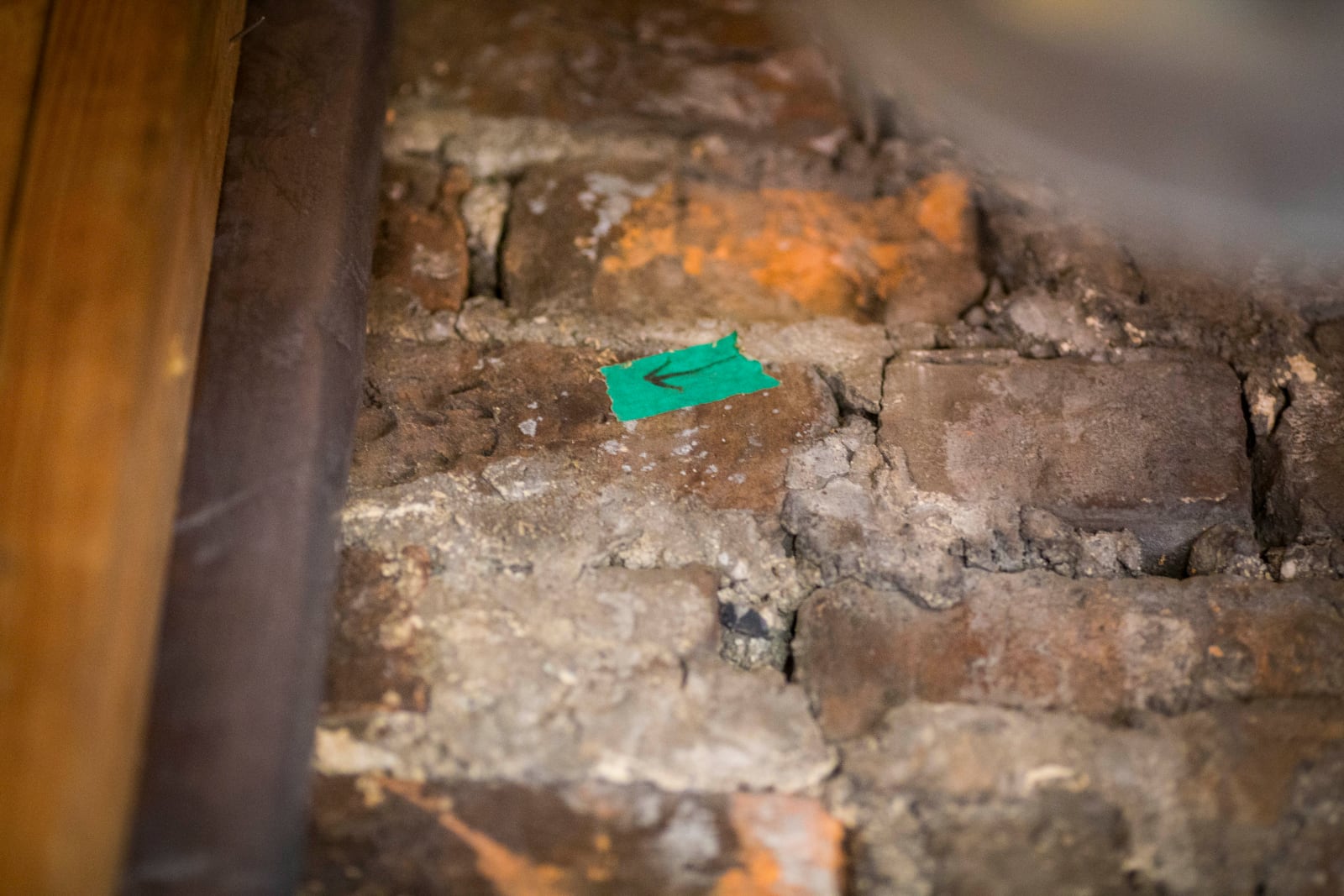 A dog's paw print (left of arrow) is seen in one of the chimney bricks at the Bray School on Wednesday, Oct 30, 2024 in Williamsburg, Va. (AP Photo/John C. Clark)