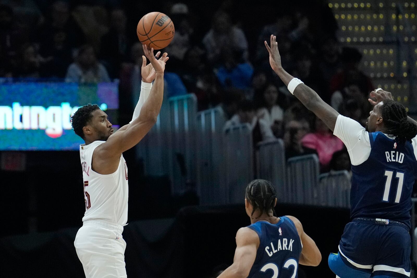 Cleveland Cavaliers guard Donovan Mitchell, left, shoots over Minnesota Timberwolves guard Jaylen Clark, center, and center Naz Reid (11) in the first half of an NBA basketball game Monday, Feb. 10, 2025, in Cleveland. (AP Photo/Sue Ogrocki)