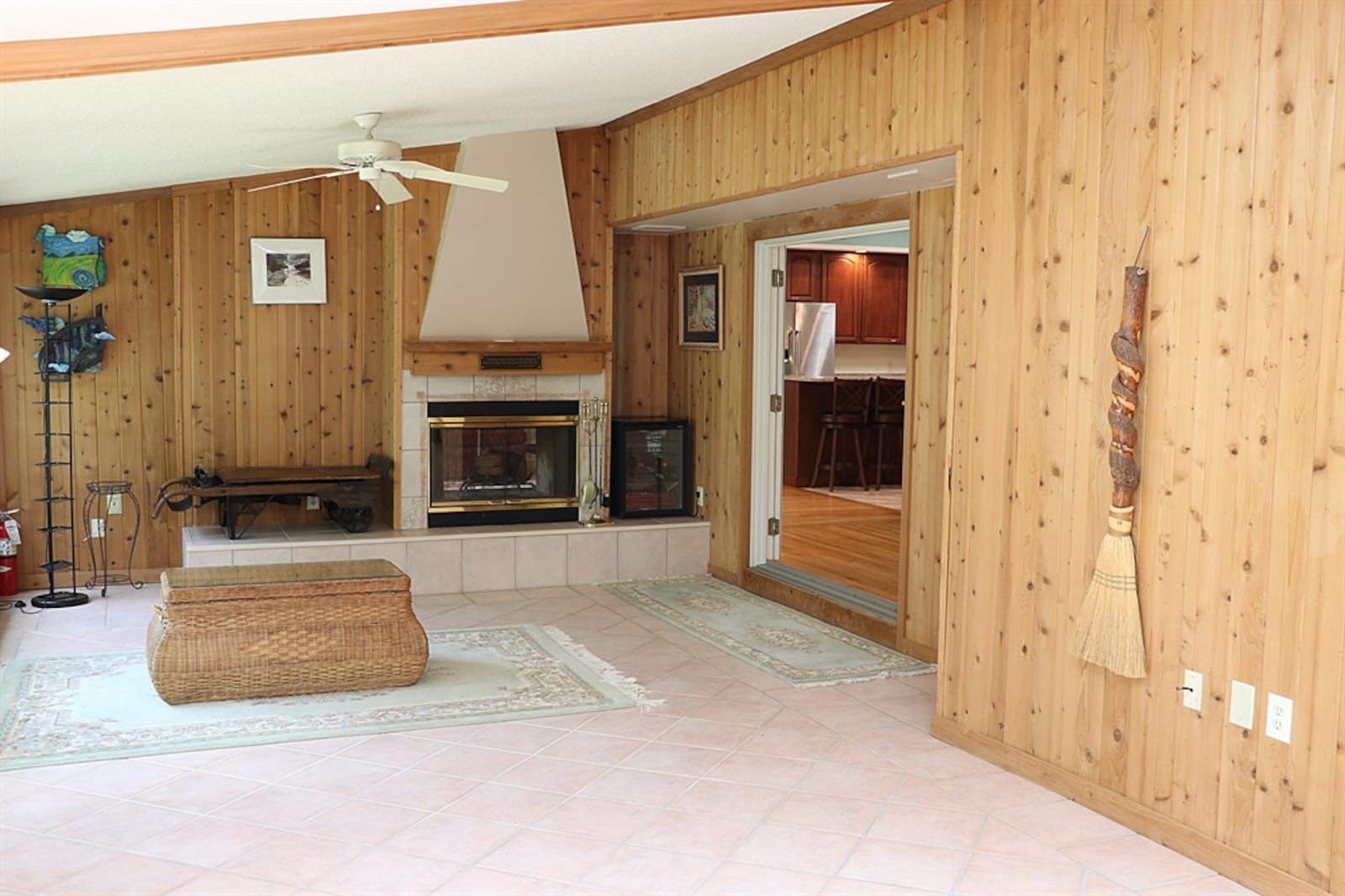 Double-glass doors open into a four-season room with knotty pine paneled walls and ceramic-tile flooring. 