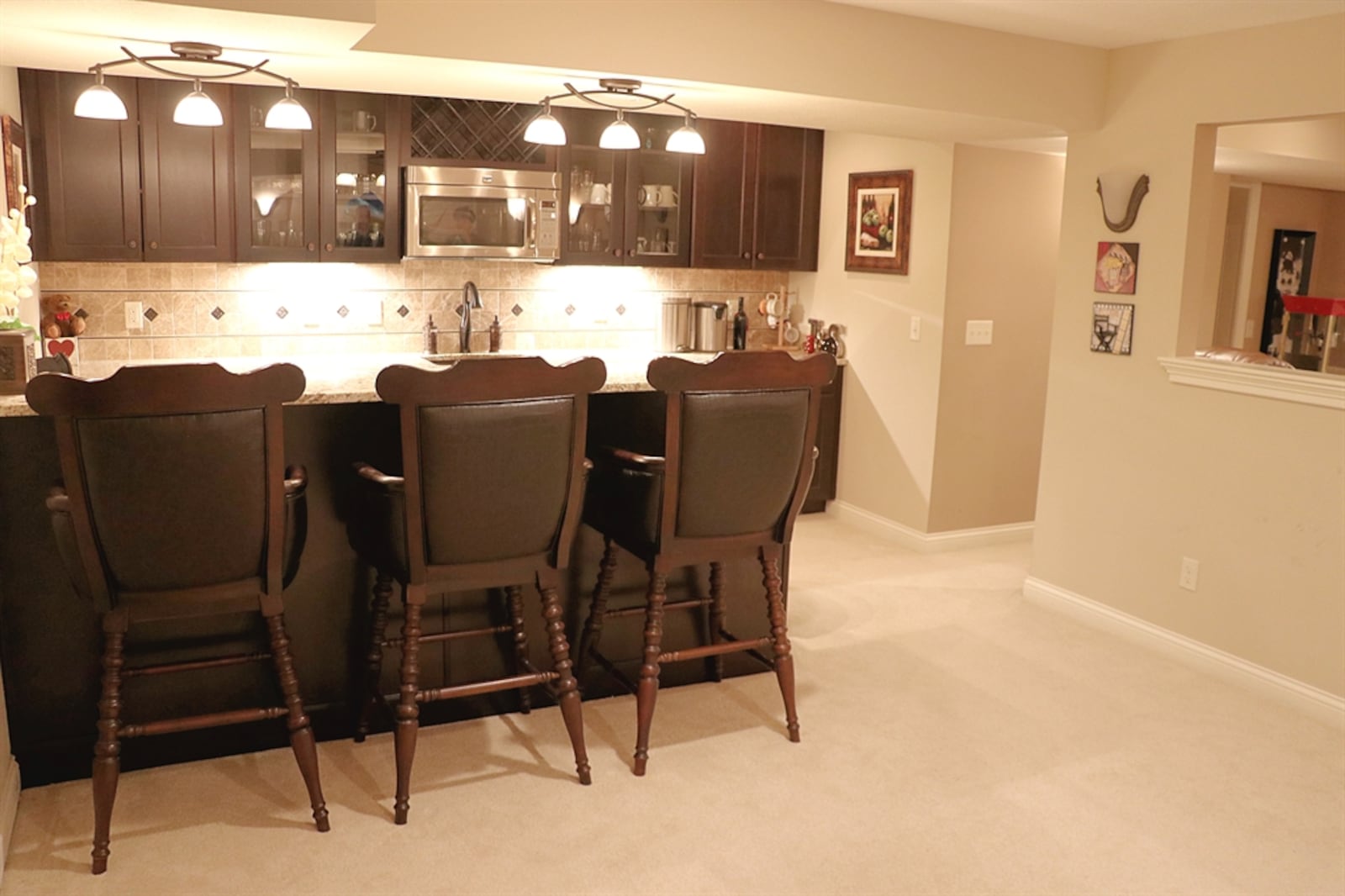 The wet bar has a peninsula counter and a wall of cabinetry that surrounds the appliances.