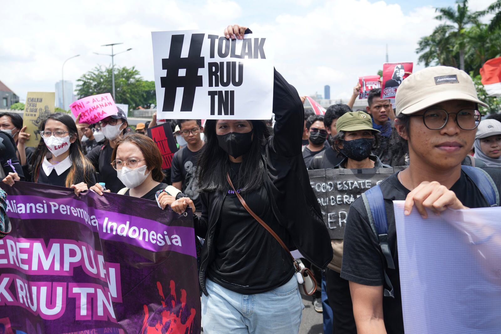 Protesters hold posters and banners as they march during a rally against the passing of a new military law allowing active military personnel to hold more civilian posts, outside the parliament in Jakarta, Indonesia, Thursday, March 20, 2025. Writing on the poster reads "Reject the Military Law". (AP Photo/Tatan Syuflana)