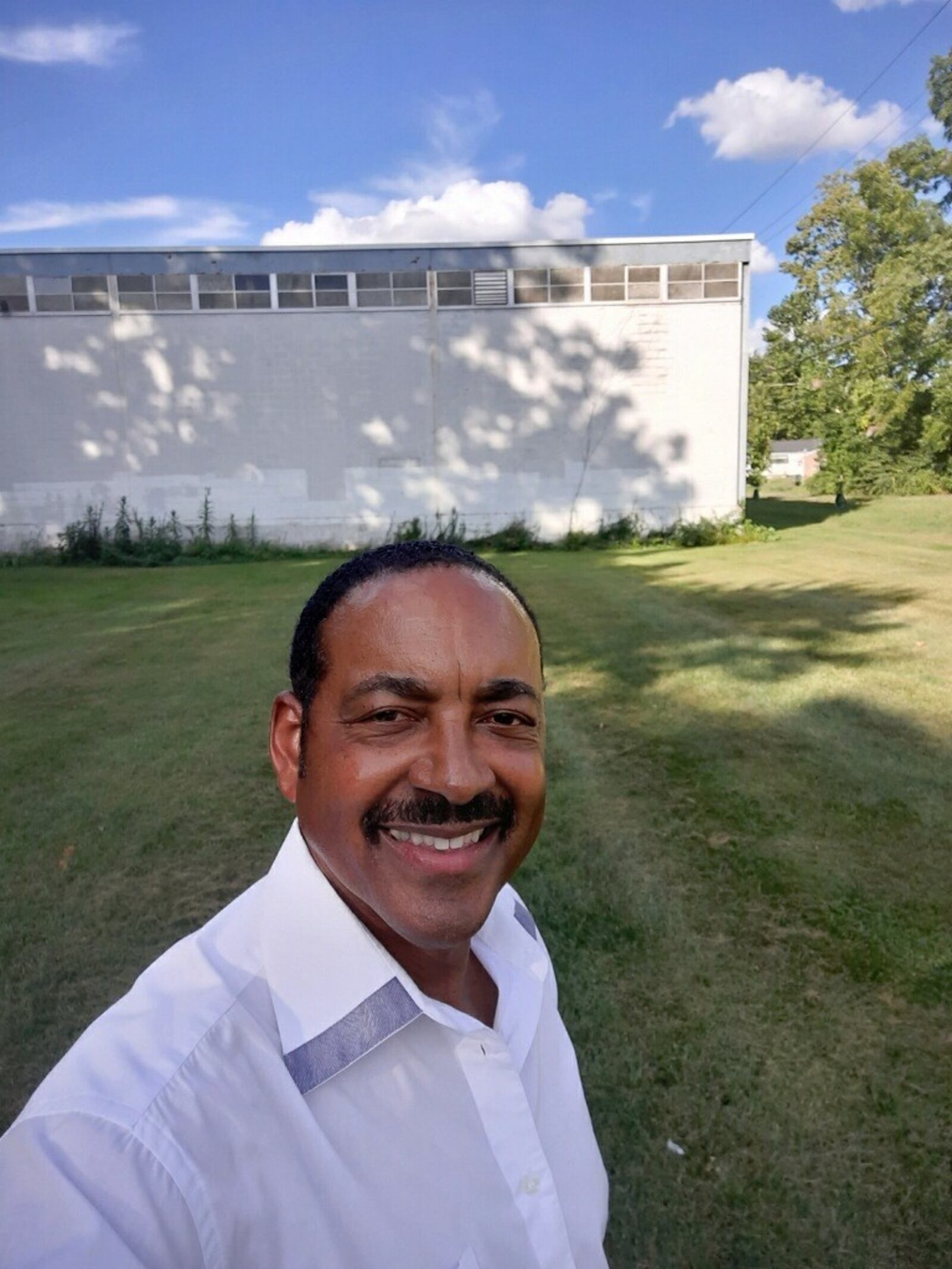 Rev. Dr. Winston Lindsey stands in front of the old lumber company – The Warehouse neighborhood kids called it – whose back wall served as the backstop for their ballfield on the empty lot next door. Lindsey, who also grew up in the neighborhood, starred in track at Fairview and in college and now is a minister in New Jersey. CONTRIBUTED