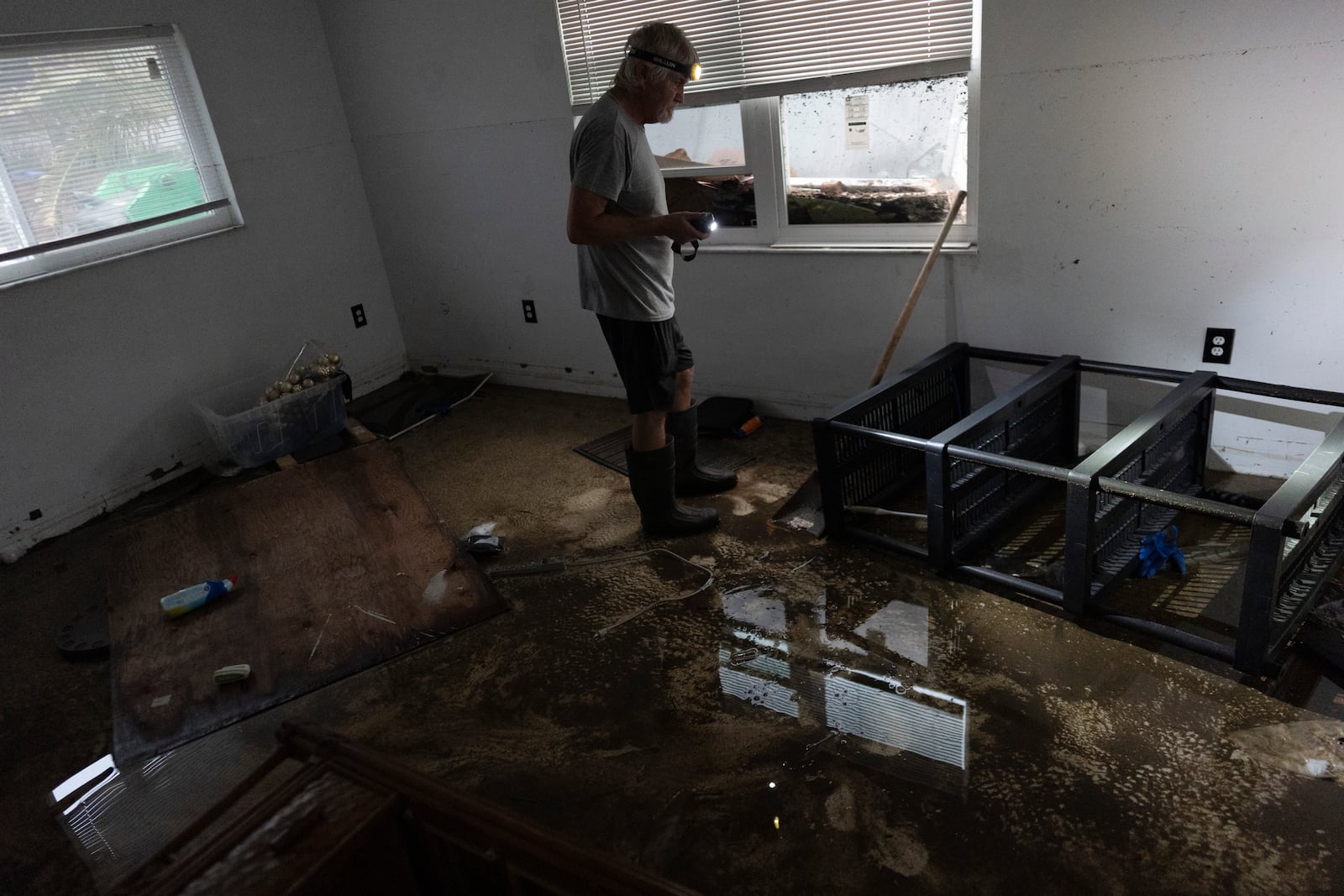 Robert Turick, 68, stands in remaining water in one of his home's bedrooms, where the high water mark from Hurricane Milton can be seen on the wall, in Englewood, Fla., Friday, Oct. 11, 2024. A small positive, said Turick, is that he hadn't yet begun repairs after Hurricane Helene brought 3-foot flood waters, and he, his dog, and his daughter were staying elsewhere when Milton flooded his home around to 5 feet. During Helene, they had to climb out his daughter's bedroom window to flee rising surge waters, after the front door became blocked. (AP Photo/Rebecca Blackwell)