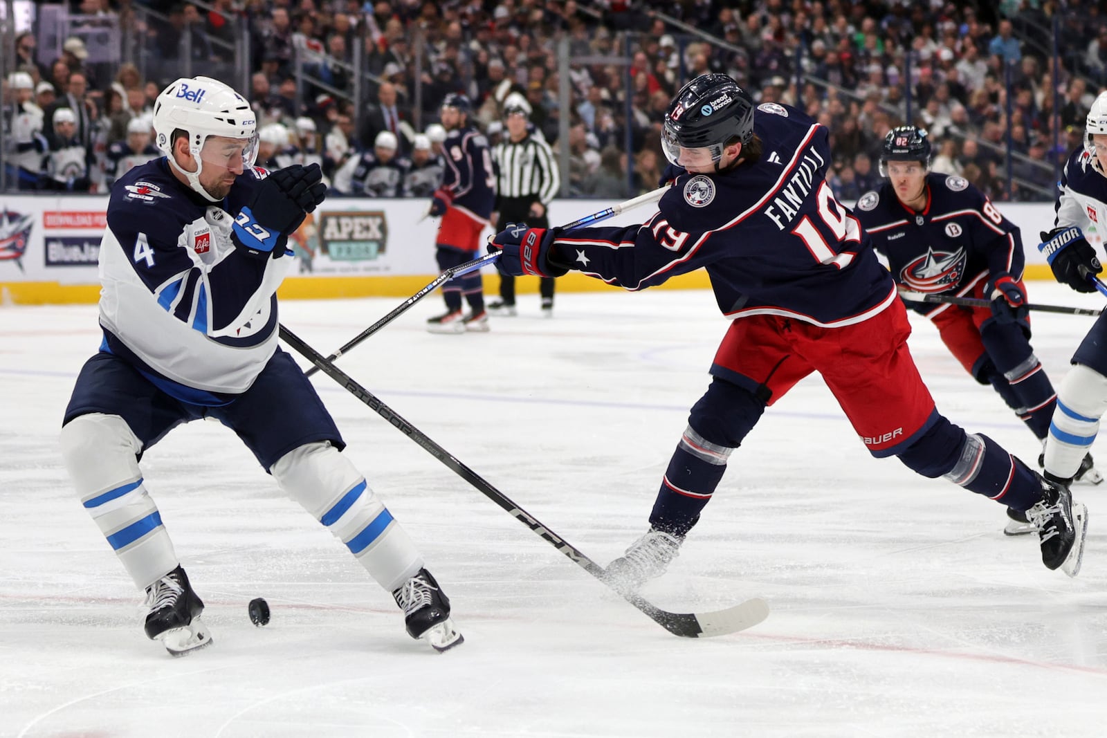 Columbus Blue Jackets forward Adam Fantilli, right, breaks his stick as he takes a shot in front of Winnipeg Jets defenseman Neal Pionk during the second period of an NHL hockey game in Columbus, Ohio, Friday, Nov. 1, 2024. (AP Photo/Paul Vernon)