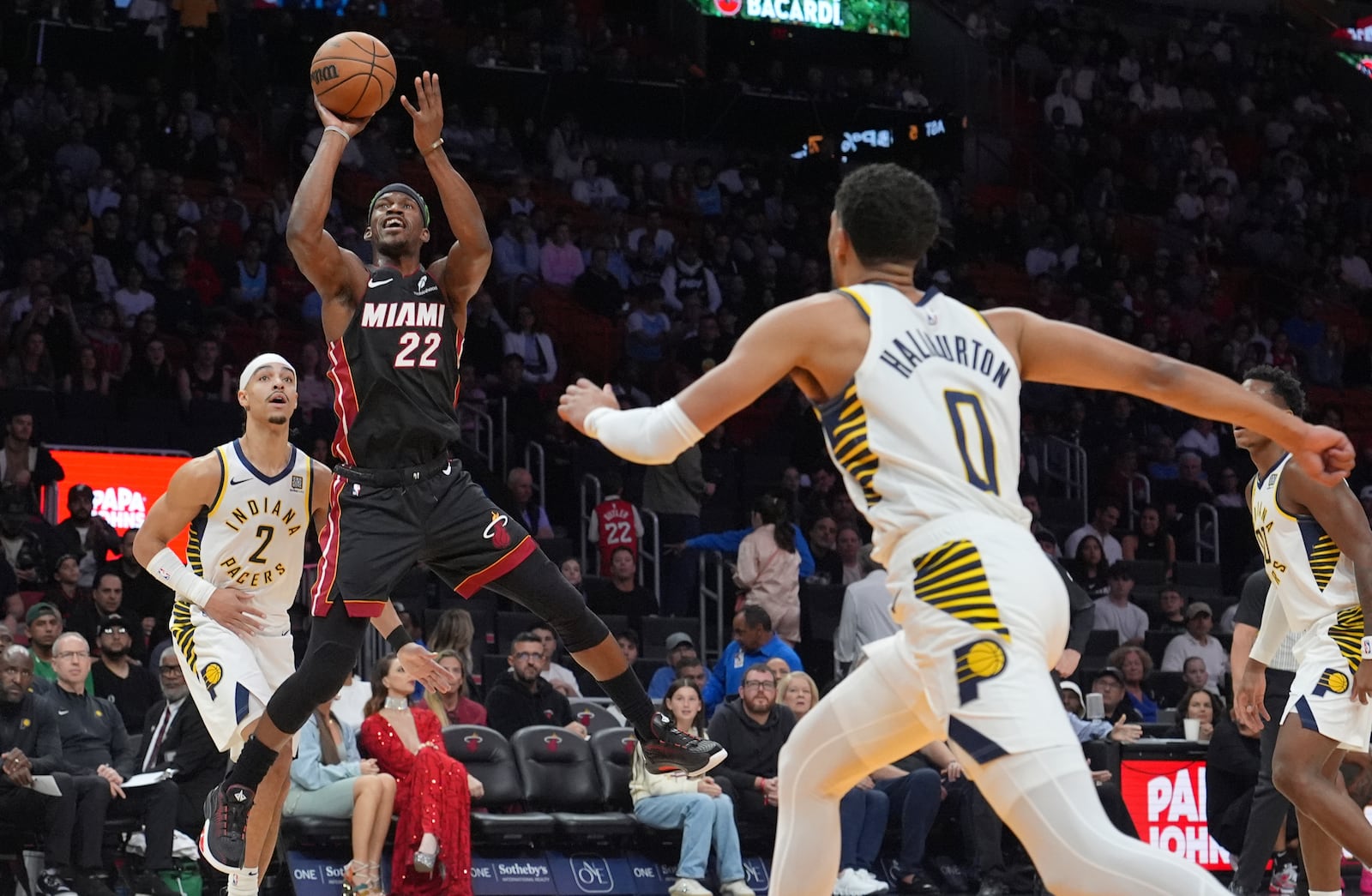 Miami Heat forward Jimmy Butler (22) shoots over Indiana Pacers guard Andrew Nembhard (2) and guard Tyrese Haliburton (0) during the first half of an NBA basketball game Thursday, Jan. 2, 2025, in Miami. (AP Photo/Lynne Sladky)