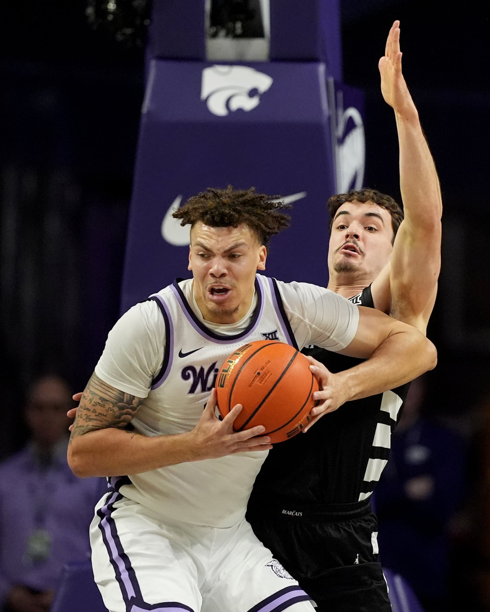 Kansas State guard Coleman Hawkins, front, looks to pass under pressure from Cincinnati guard Connor Hickman, back, during the first half of an NCAA college basketball game, Monday, Dec. 30, 2024, in Manhattan, Kan. (AP Photo/Charlie Riedel)