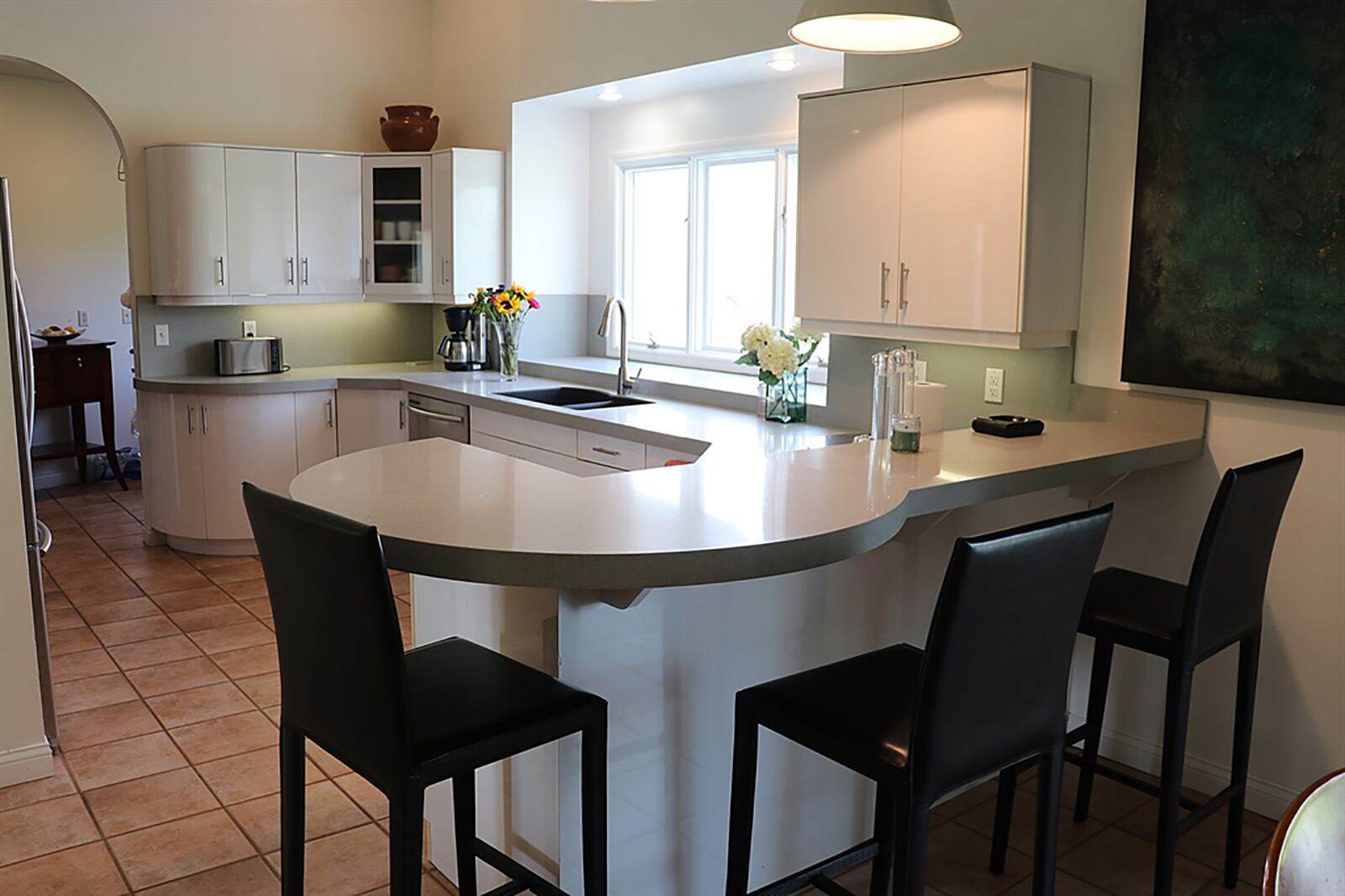 The kitchen has an abundance of storage, featuring a combination of cherry and white lacquer cabinets. Granite countertops curve over the white cabinetry. Triple windows are above a double sink. CONTRIBUTED PHOTO BY KATHY TYLER