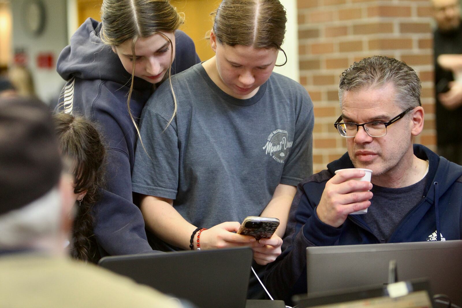 Nia McKinnon and Elizabeth Hintz, both 14, look at their phones at a charging station located in the Senior Center in Issaquah, Wash., Friday, Nov. 22, 2024. (AP Photo/Manuel Valdes)