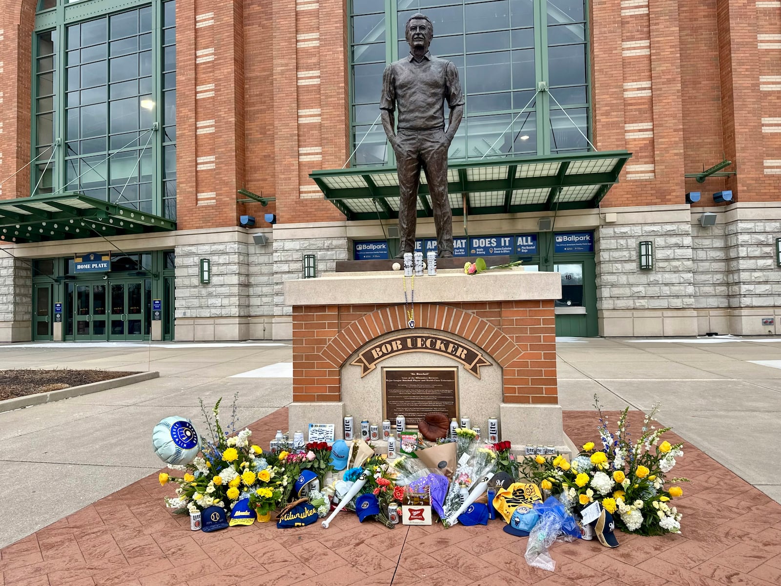 Items are left at the base of a statue of Bob Uecker outside American Family Field in Milwaukee, Thursday, Jan. 16, 2025. (AP Photo/Steve Megargee)