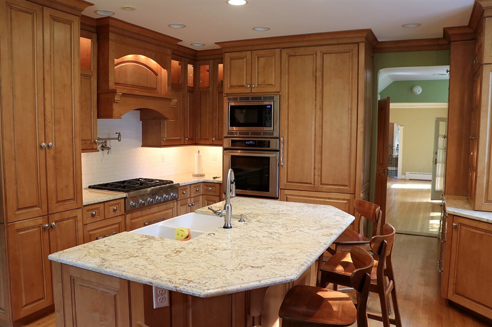 In the kitchen, an island provides an extended counter for bar seating. Above the gas cooktop is a pot-filler faucet. 