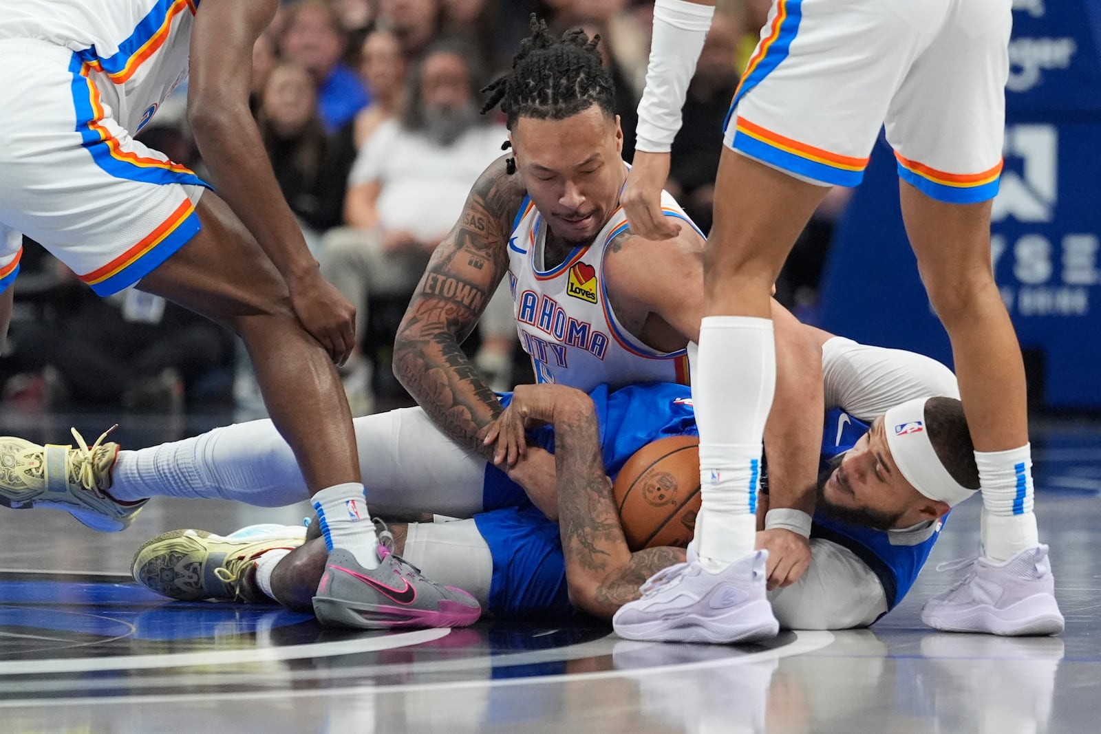 Oklahoma City Thunder guard Luguentz Dort, center top, and Dallas Mavericks center Daniel Gafford, bottom, tussle for the ball during the first half of an NBA basketball game Friday, Jan. 17, 2025, in Dallas. (AP Photo/LM Otero)