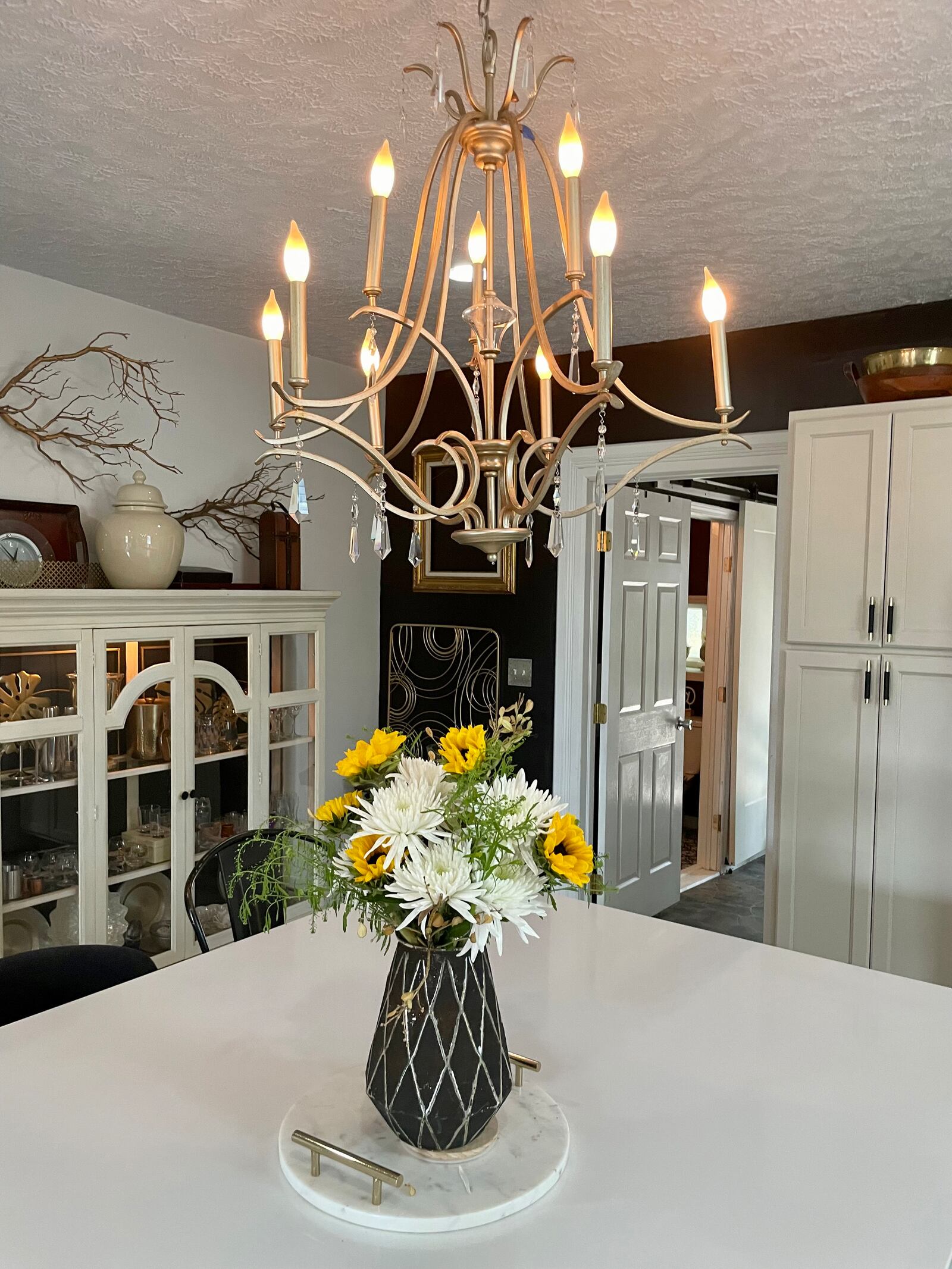 Terri Miller purchased this chandelier, which she installed in her kitchen during renovations, at a community garage sale for $20. The display case (left) was a thrift-store find for $100. Photo by Robin McMacken