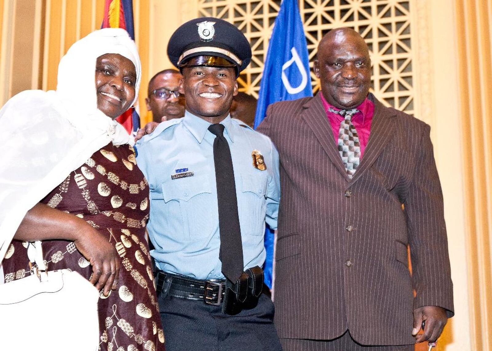 Police Officer Ndayisaba Ramadhan is flanked by his mother, Selina, and father, Issa, at the 108th Recruit Class Graduation Ceremony Friday night at Stivers High School. Floyd Thomas Jr./CONTRIBUTED