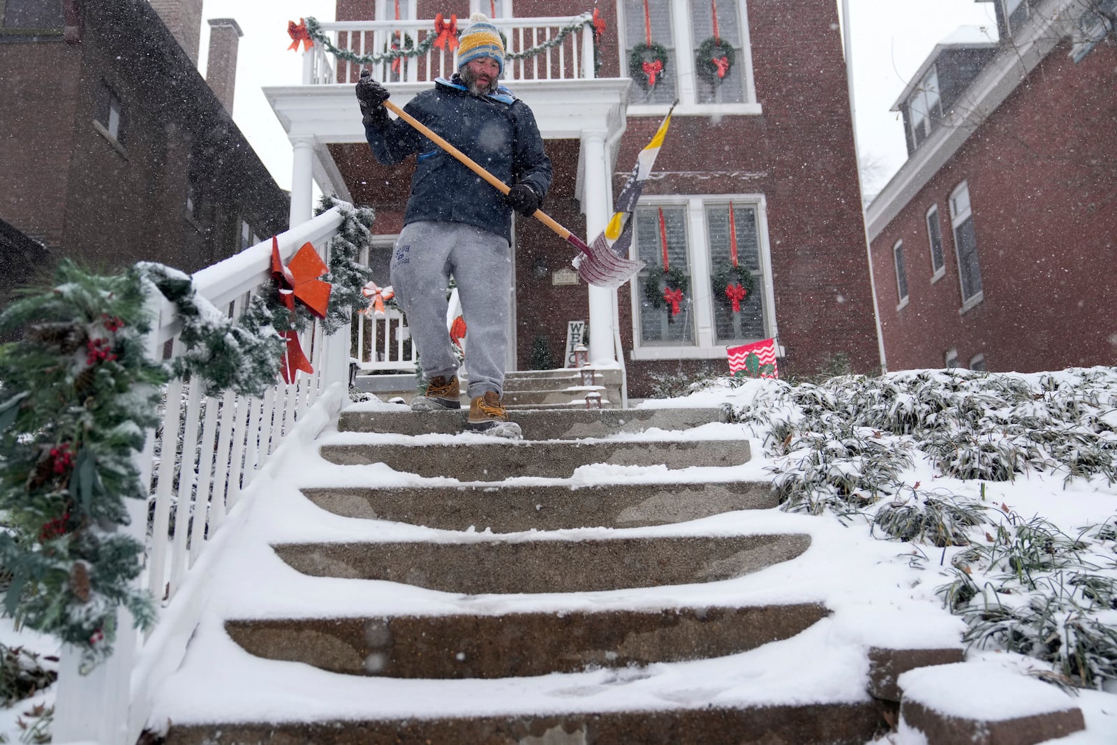 Paul Cullmann clears snow from steps outside his home Sunday, Jan. 5, 2025, in St. Louis. (AP Photo/Jeff Roberson)