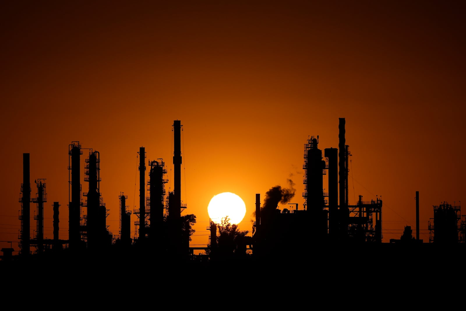 FILE - The CHS oil refinery is silhouetted against the setting sun Sept. 28, 2024, in McPherson, Kan. (AP Photo/Charlie Riedel, File)