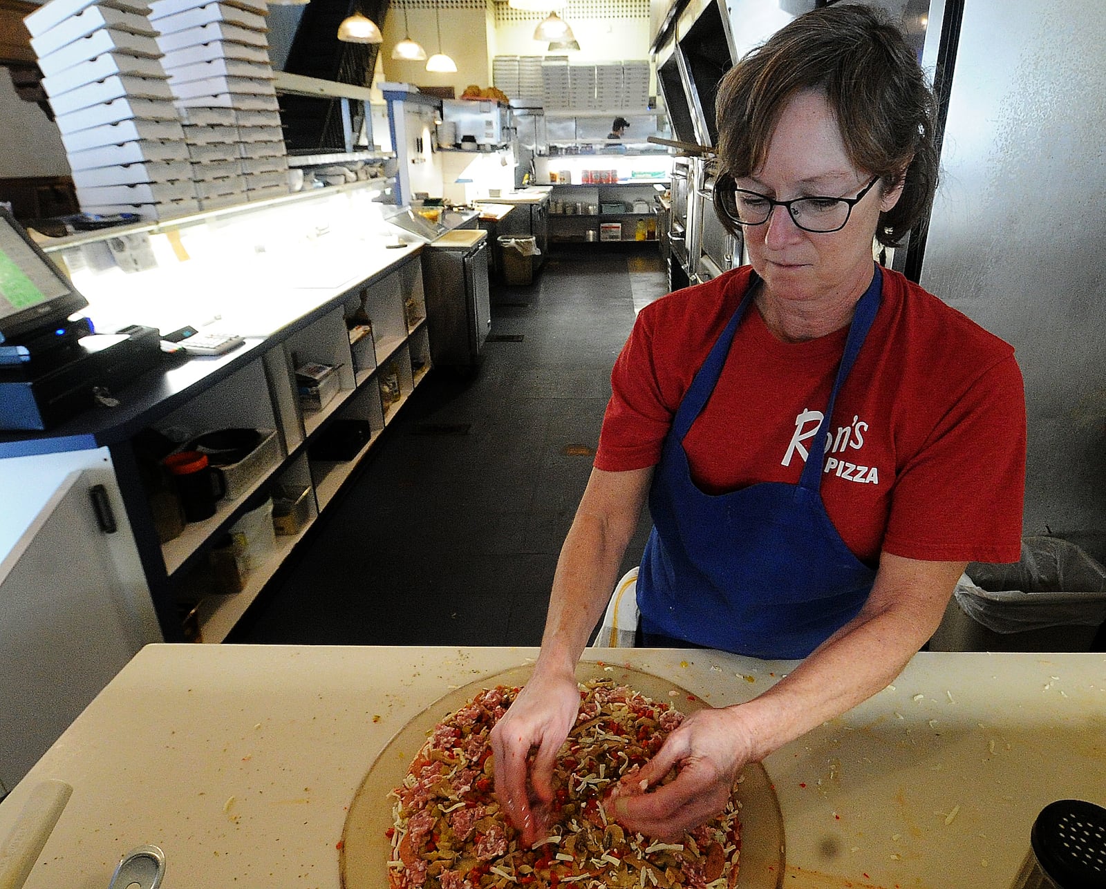 Abbie Romero, the daughter of Ron's Pizza founder Ron Holp, makes a pizza Thursday, Jan. 5, 2023 at the downtown Miamisburg restaurant. The business is wrapping up a renovation effort that has taken more than a year. MARSHALL GORBY/STAFF