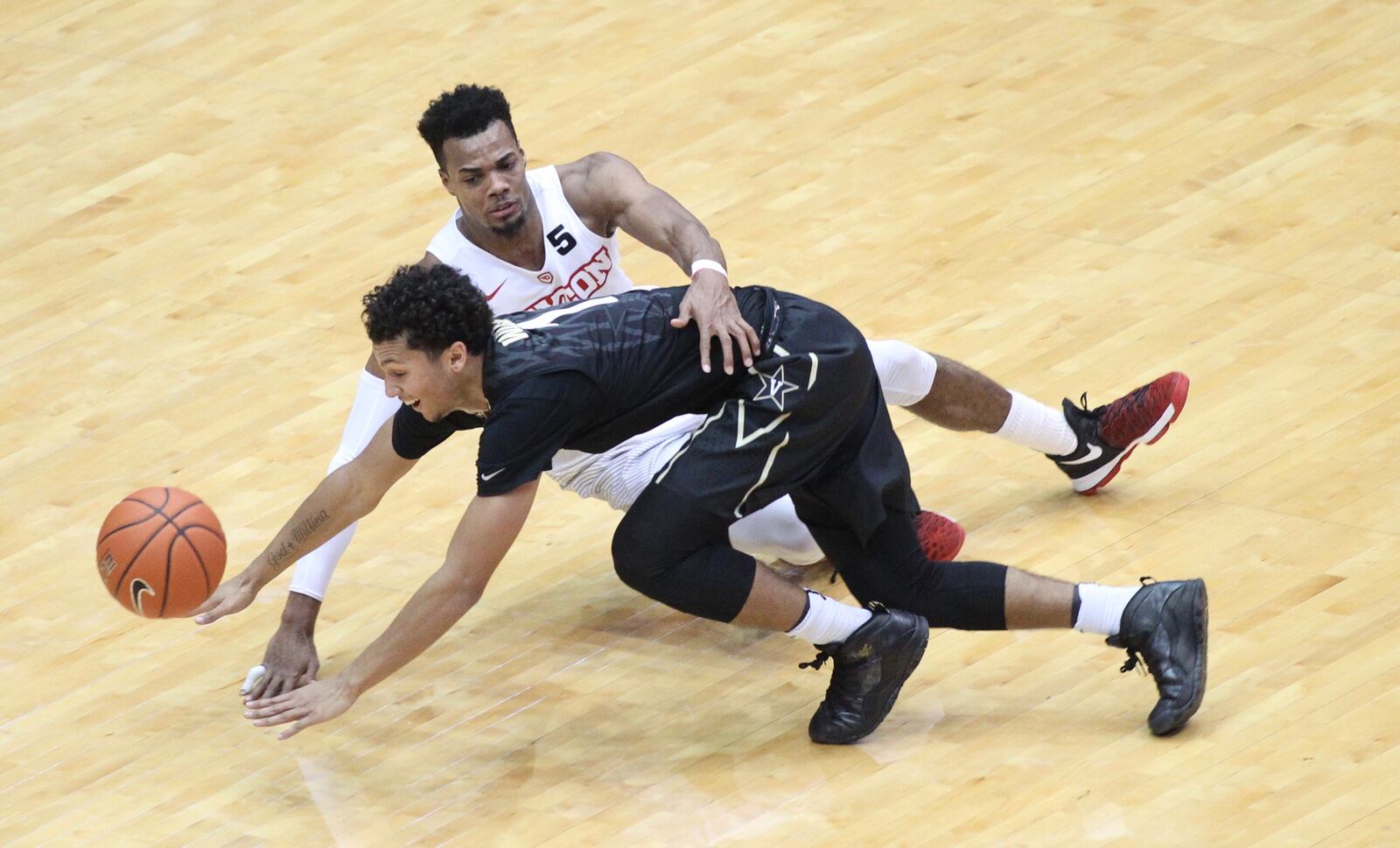 Dayton's Charles Cooke, top, chases a loose ball against Vanderbilt's Payton Willis on Wednesday, Dec. 21, 2016, at UD Arena. David Jablonski/Staff