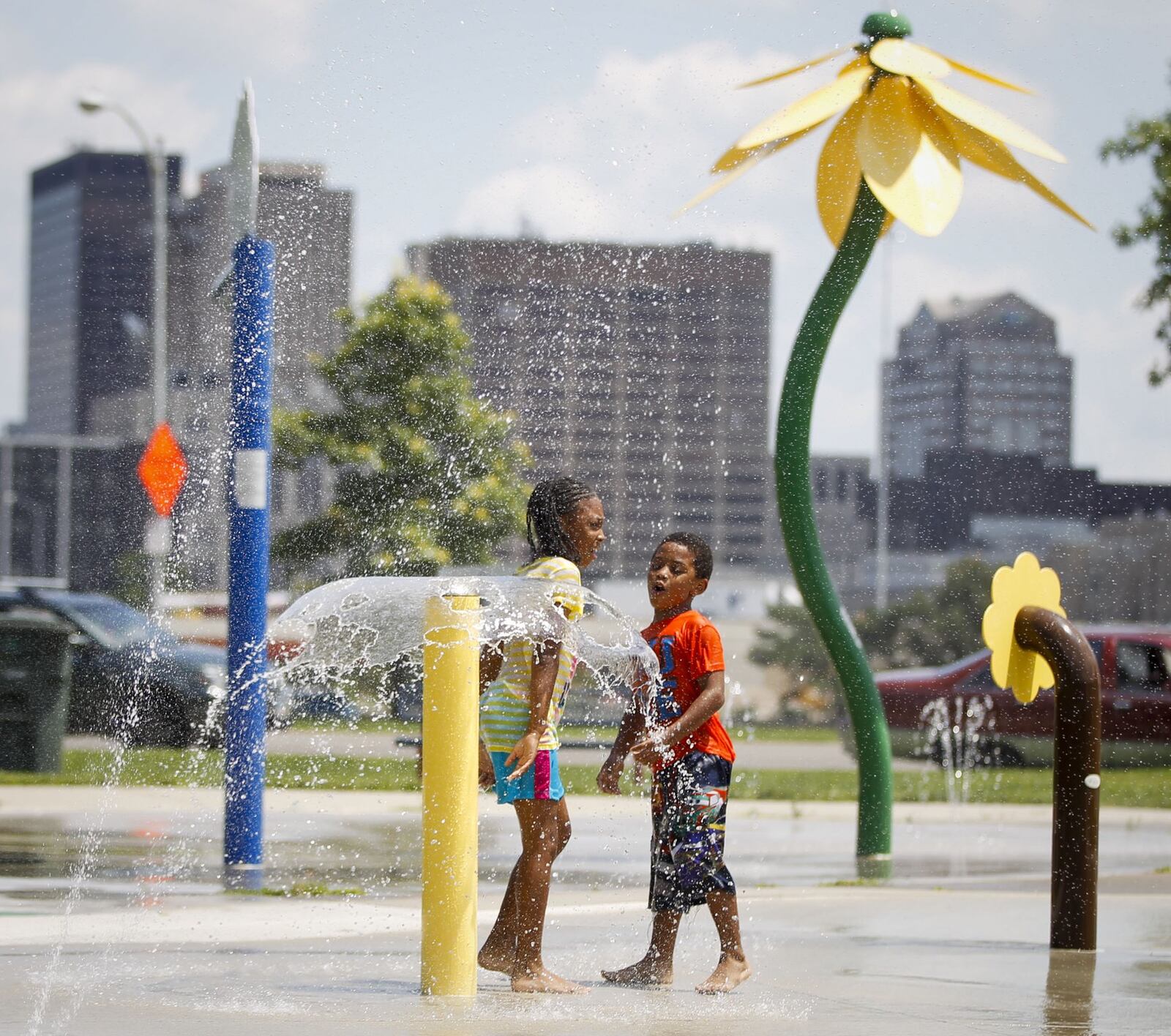 Sister and brother Amariya Hill, 9, left, and Khirya Hill, 5, play on the splash pad at McIntosh Park in Dayton on Thursday during an outing with their grandmother. A rare stretch of dry weather is expected to last into the weekend. TY GREENLEES / STAFF