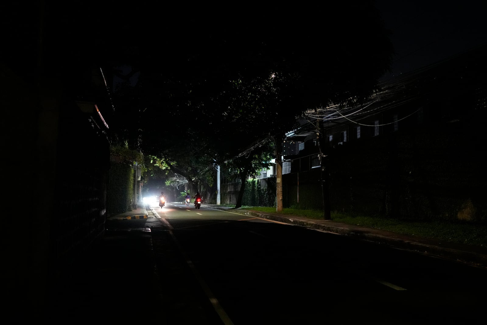 Vehicles pass by a dimly lit portion of Balete Drive in Quezon City, Philippines, Friday, Oct. 25, 2024. (AP Photo/Aaron Favila)