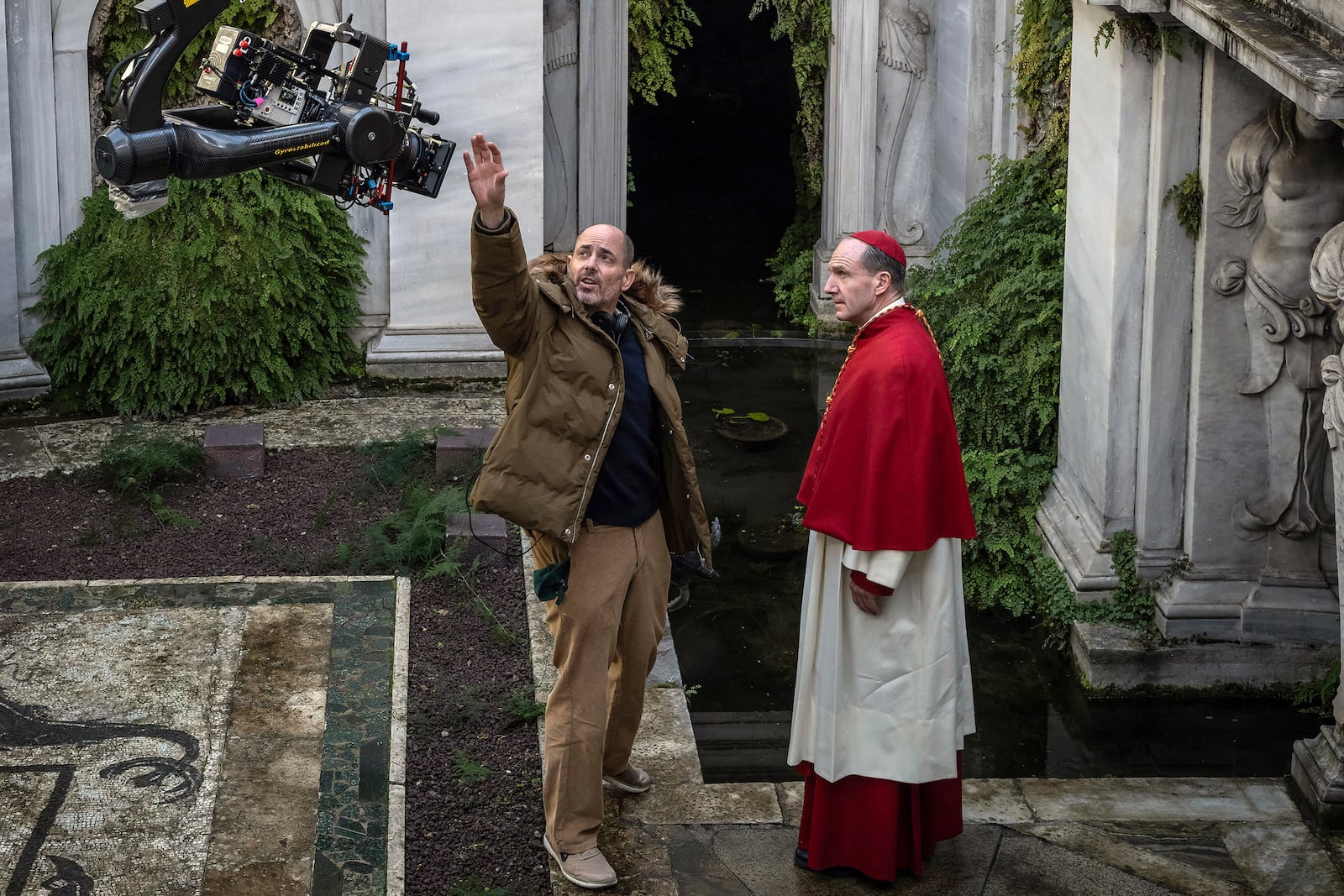 This image released by Focus features shows director Edward Berger, left, and actor Ralph Fiennes on the set of "Conclave." (Philippe Antonello/Focus Features via AP)