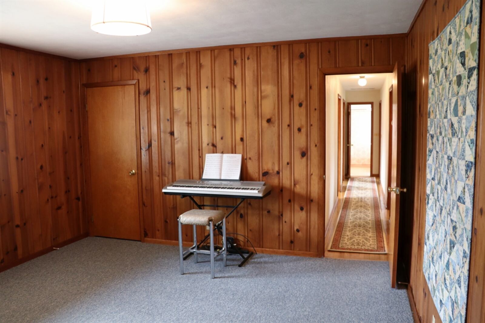 A family room has knotty pine-paneled walls, a rear-facing window and a closet. 