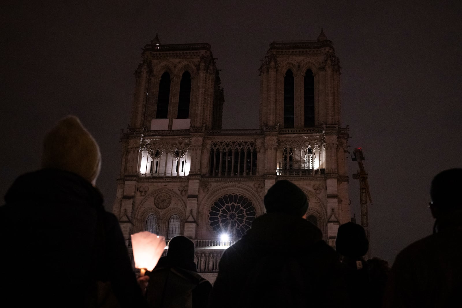 People watch Notre-Dame cathedral after a procession to bring the Virgin Mary statue from Saint-Germain l'Auxerrois church to the cathedral, Friday, Nov. 15, 2024 in Paris. (AP Photo/Louise Delmotte)