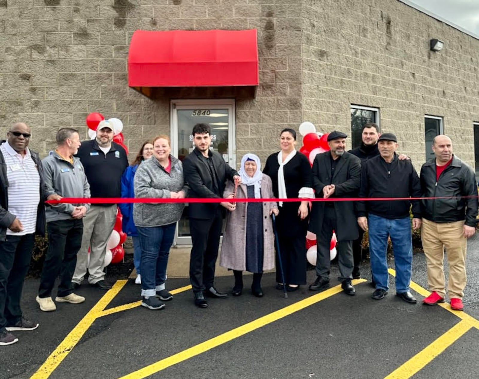 Osman Khalilov, center, cuts the ribbon during the grand opening ceremony for his business Leo Auto Sales in Huber Heights on Saturday. CONTRIBUTED