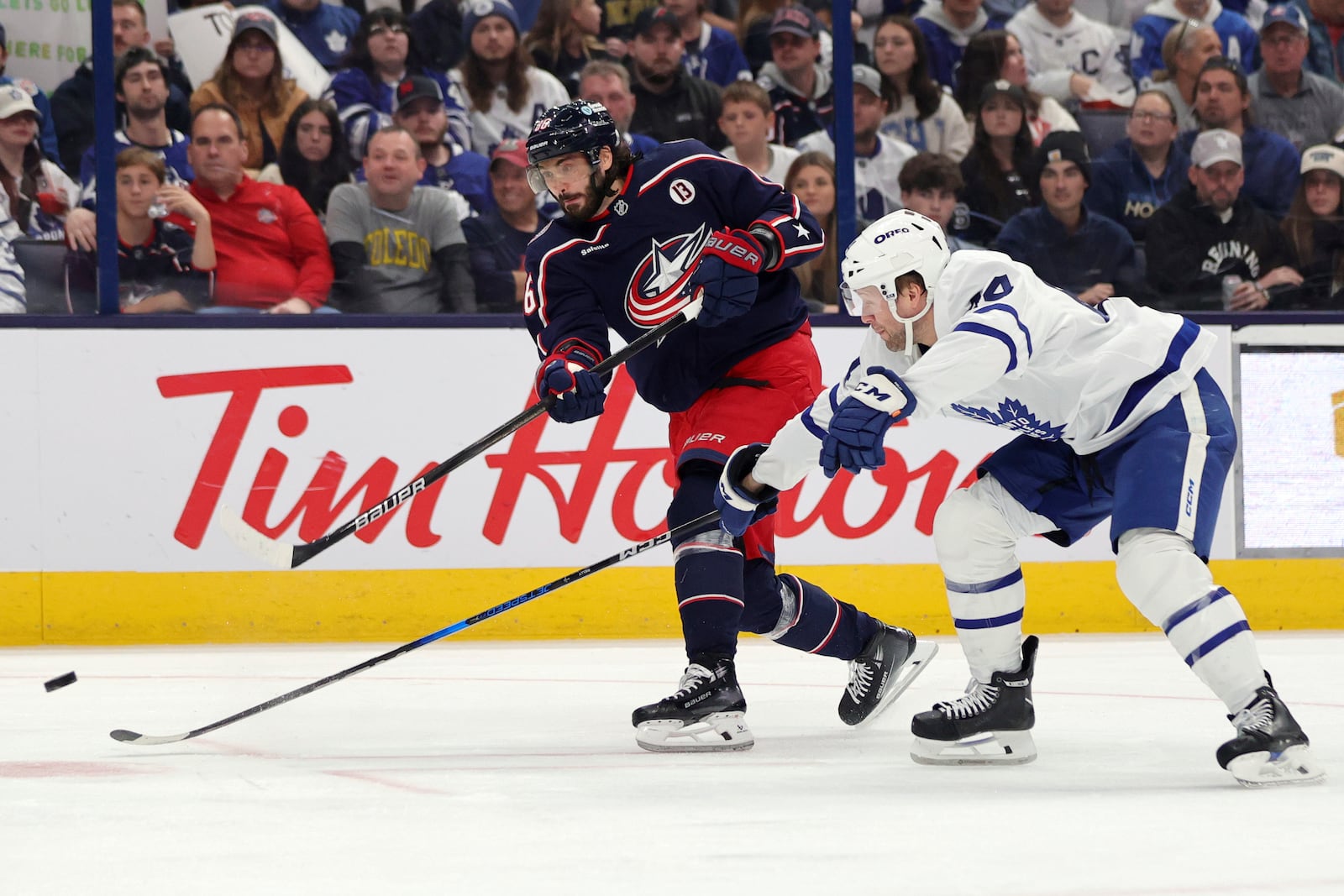 Columbus Blue Jackets forward Kirill Marchenko, left, shoots the puck in front of Toronto Maple Leafs defenseman Morgan Rielly during the second period of an NHL hockey game in Columbus, Ohio, Tuesday, Oct. 22, 2024. (AP Photo/Paul Vernon)