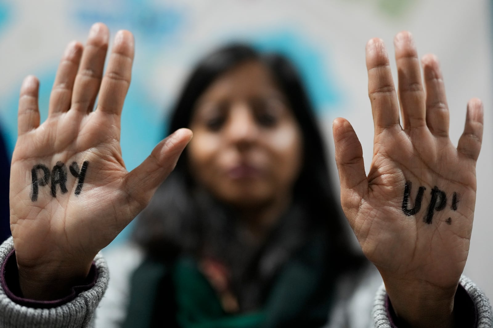 A demonstrator displays hands that reads "pay up" during a protest for climate finance at the COP29 U.N. Climate Summit, Saturday, Nov. 23, 2024, in Baku, Azerbaijan. (AP Photo/Rafiq Maqbool)