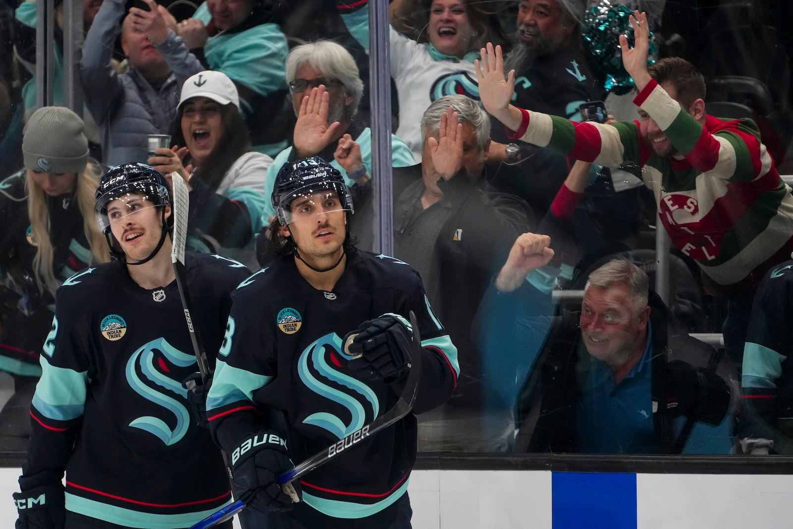 Fans cheer as Seattle Kraken left wing Brandon Tanev, right, celebrates his goal against the Columbus Blue Jackets with teammate Tye Kartye, left, during the second period of an NHL hockey game Tuesday, Nov. 12, 2024, in Seattle. (AP Photo/Lindsey Wasson)