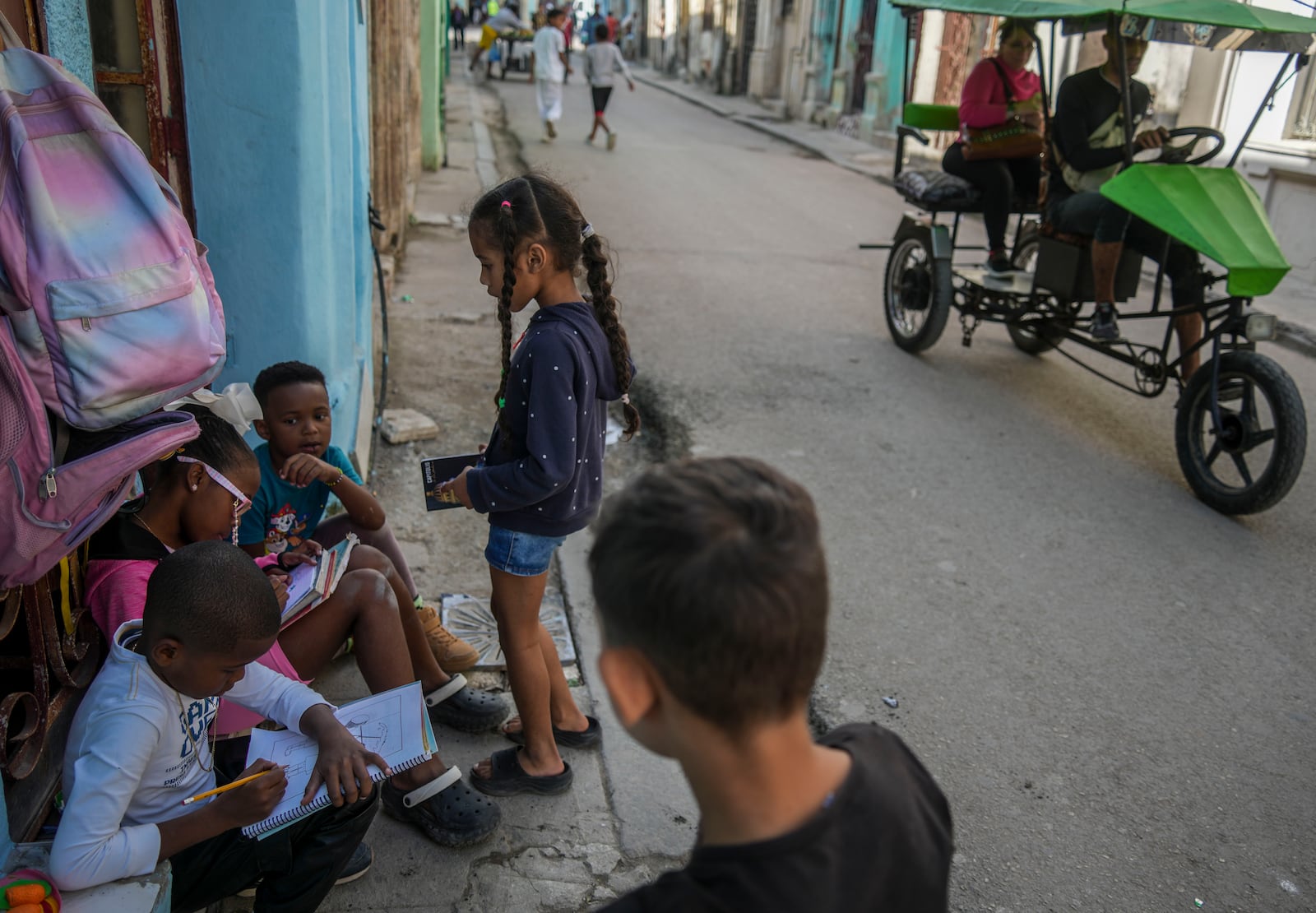 Children do their homework on a front doorstep during a blackout in Havana, Cuba, Wednesday, Dec. 4, 2024. (AP Photo/Ramon Espinosa)