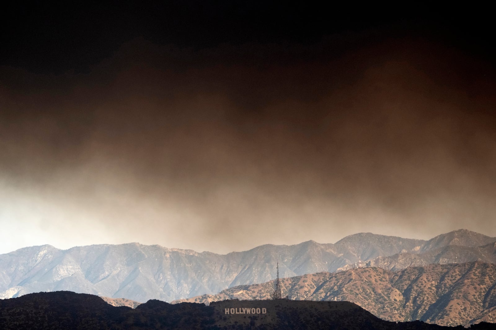 Thick heavy smoke from wildfires passes over the Hollywood sign in Los Angeles on Wednesday, Jan. 8, 2025. (AP Photo/Richard Vogel)