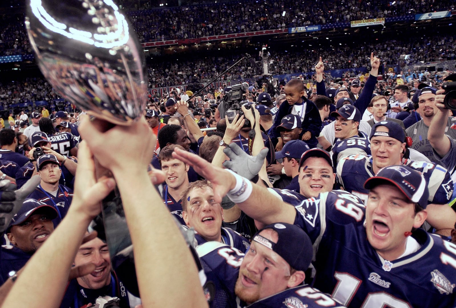 FILE - New England Patriots players reach out to touch the Vince Lombardi Trophy after the Patriots defeated the St. Louis Rams 20-17 to win NFL football Super Bowl 36 in New Orleans, Feb. 3, 2002. (AP Photo/David J. Philli, File)