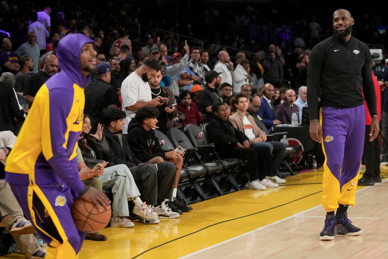 Los Angeles Lakers guard Bronny James shoots as forward LeBron James (23) watches on before an NBA basketball game against the Phoenix Suns in Los Angeles, Friday, Oct. 25, 2024. (AP Photo/Eric Thayer)