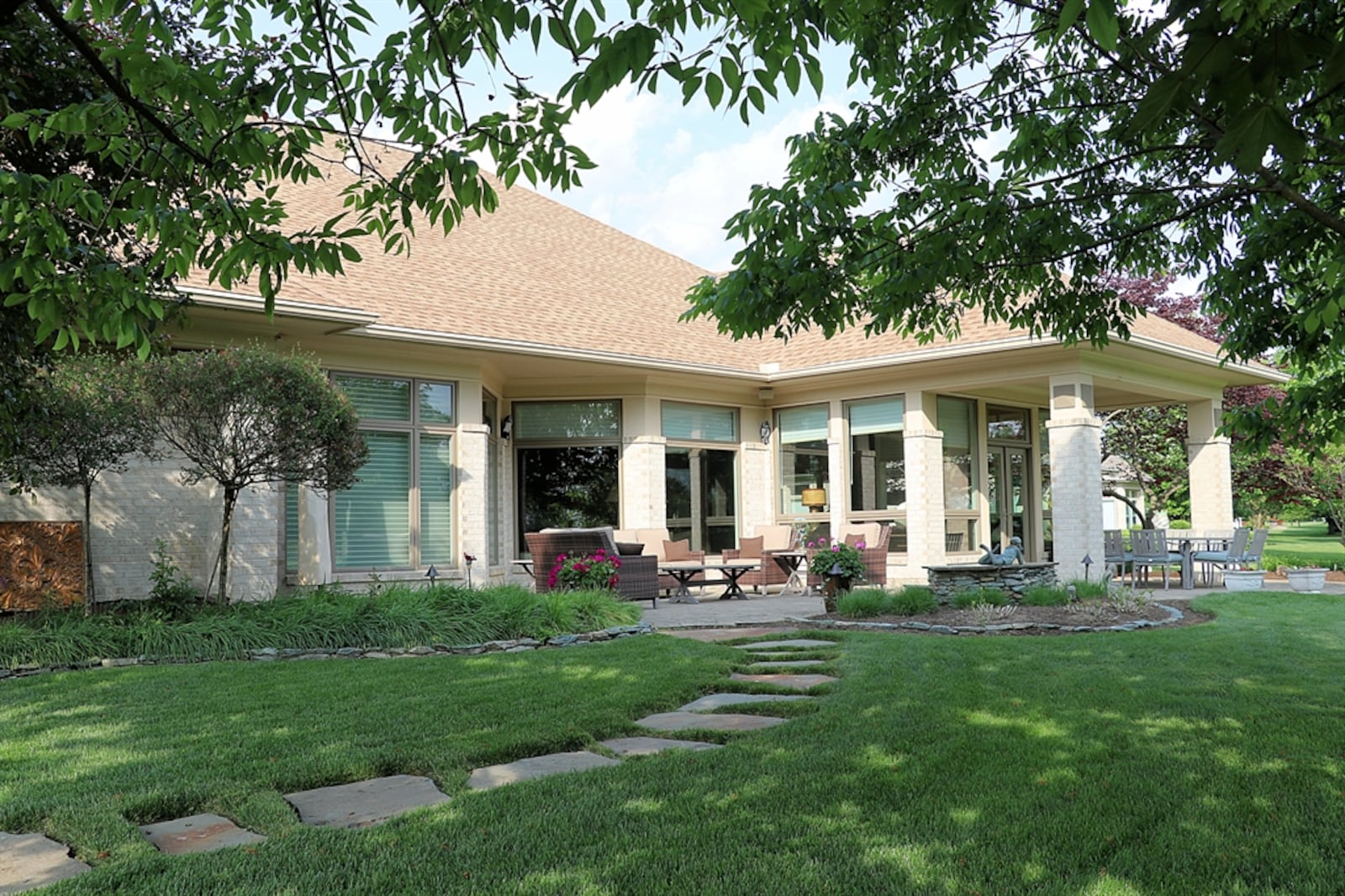 Enhanced gardens add to the views with a stone path to a garden nook from the paver-brick backyard patio. 