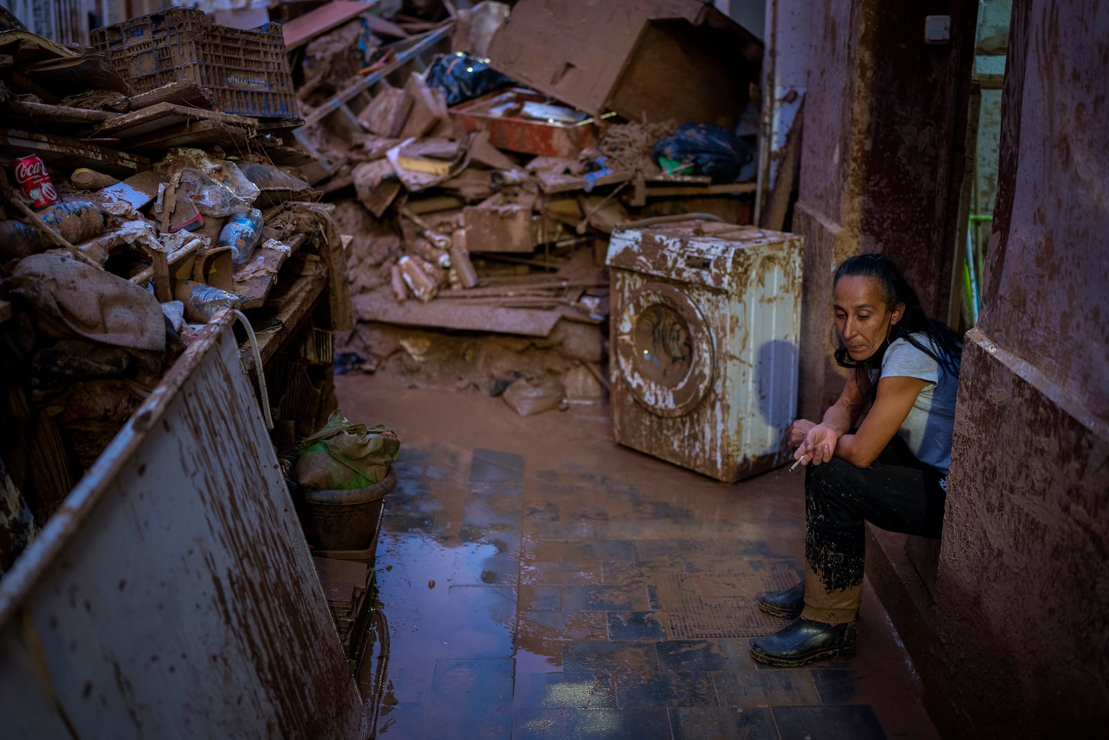 Maria Carmen, 54, sits next to her belongings outside her house after the floods in Paiporta, Valencia, Spain, Tuesday, Nov. 5, 2024. (AP Photo/Emilio Morenatti)