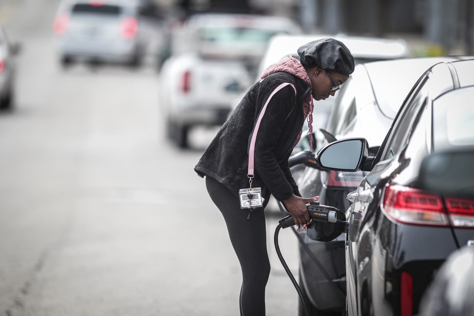 Jordan Bernard unplugs her KIA Optima hybrid from a charging station near the intersection of Patterson and Monument in this 2021 file photo. Nearly 30 sites in the Dayton area were awarded state funds for electric vehicle charging ports as part of $3.25 million in grants announced by the Ohio Environmental Protection Agency.