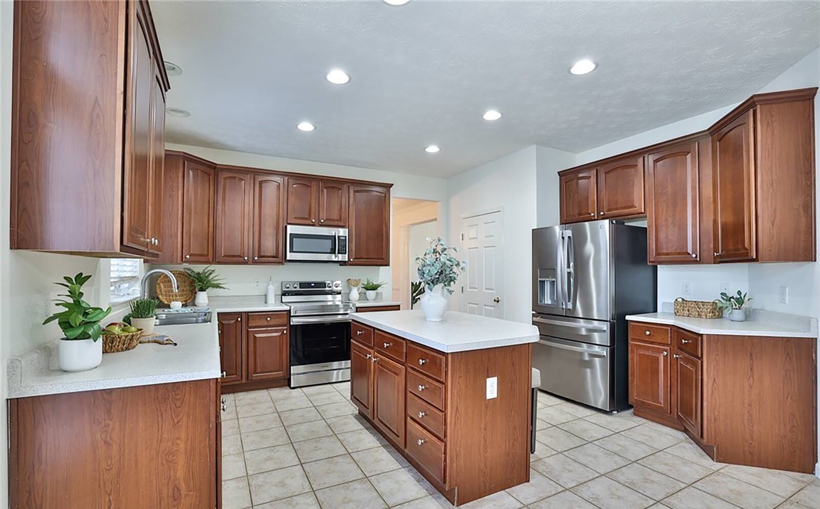 The kitchen has newer stainless appliances and an island with seating as well as a pantry and exterior door in the breakfast area leading out to the composite deck overlooking a golf course.