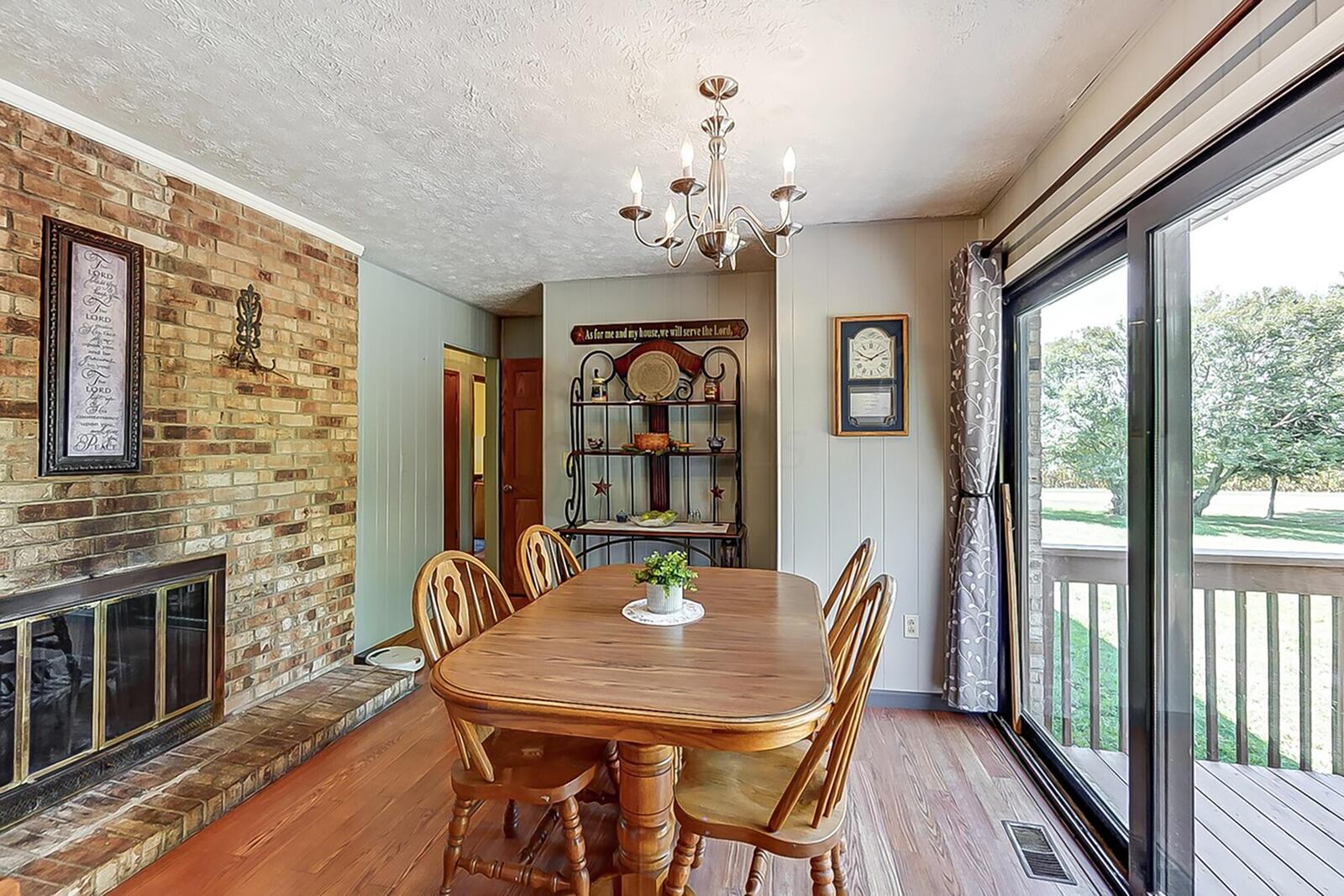 the dining room has hardwood flooring and a brick woodburning fireplace with glass doors. There is a sliding glass door leading to the rear deck.