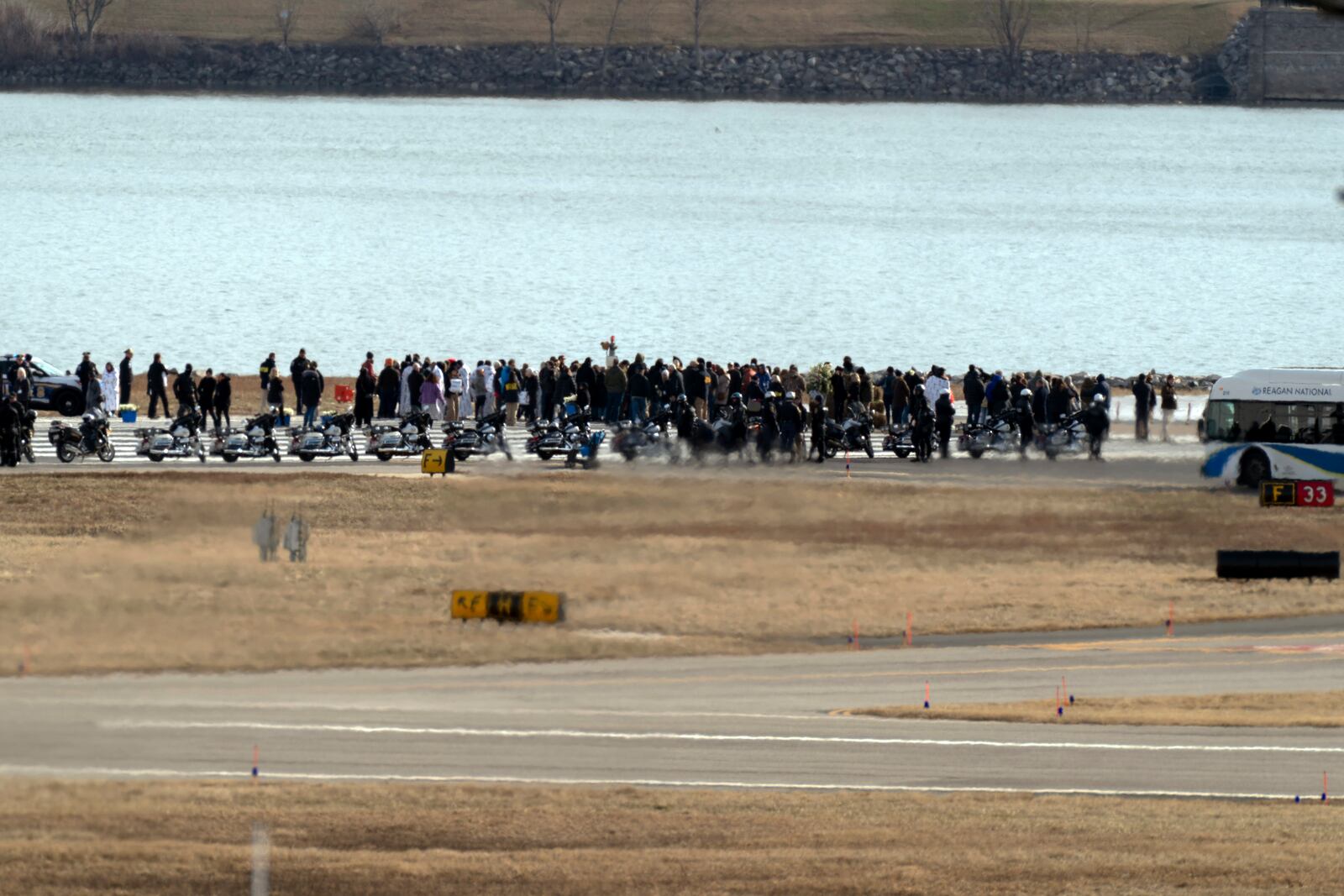 Families of the victims of a mid-air collision between an American Airlines jet and an Army helicopter stand near the wreckage site in the Potomac River at the end of the runway 33 from Ronald Reagan Washington National Airport, Sunday, Feb. 2, 2025, in Arlington, Va. (AP Photo/Jose Luis Magana)