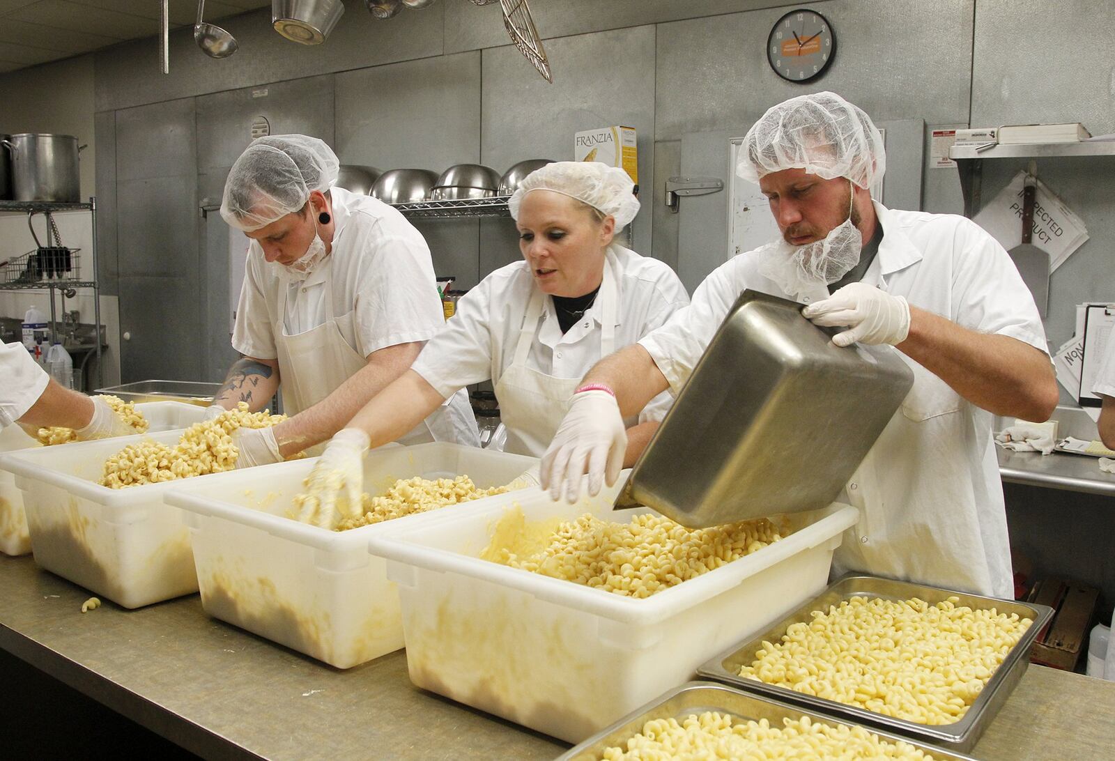 Travis Day, Kerri Metcalf and Mac Burggraf, employees of Scratch Food, make macaroni and cheese for prepared meals that will go to Pink Ribbon Girls clients. LISA POWELL / STAFF