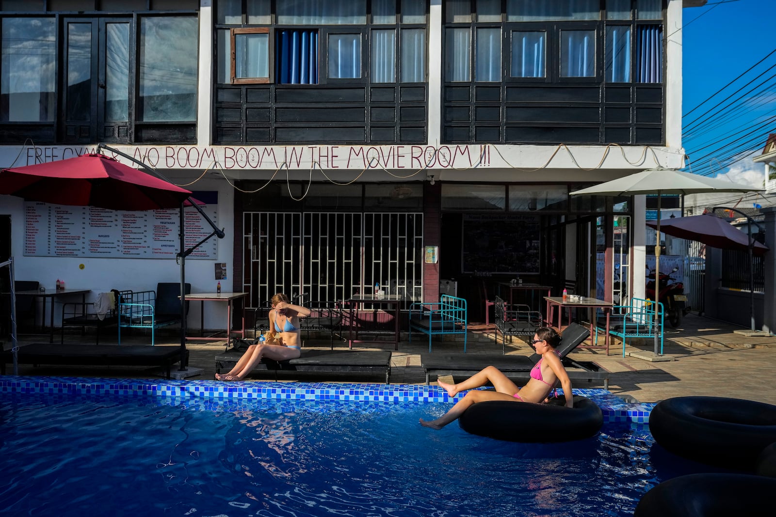 Foreign tourists relax at a swimming pool at Nana Backpack hostel in Vang Vieng, Laos, Tuesday, Nov. 19, 2024. (AP Photo/Anupam Nath)