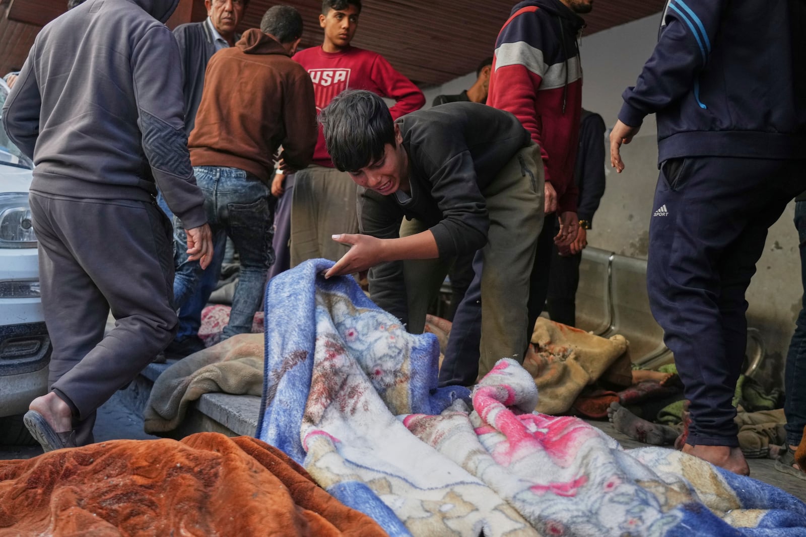 A boy reacts as he looks at the body of a person killed during overnight Israeli army airstrikes across the Gaza Strip in the yard of the Al-Ahli hospital in Gaza City, Tuesday, March 18, 2025. (AP Photo/Jehad Alshrafi)