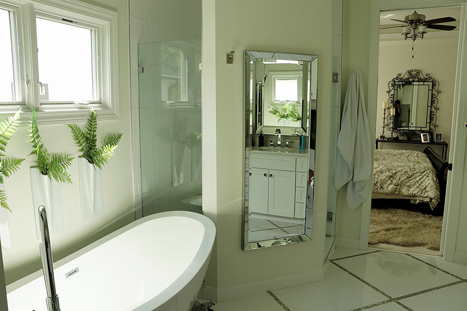 The first-floor main bedroom has tray ceiling with built-in speakers and accent lighting. A pocket door opens into the bathroom oasis with glass and ceramic-tile surround shower that has multiple shower heads and a free-standing soaking tub with transom window above. CONTRIBUTED PHOTO BY KATHY TYLER