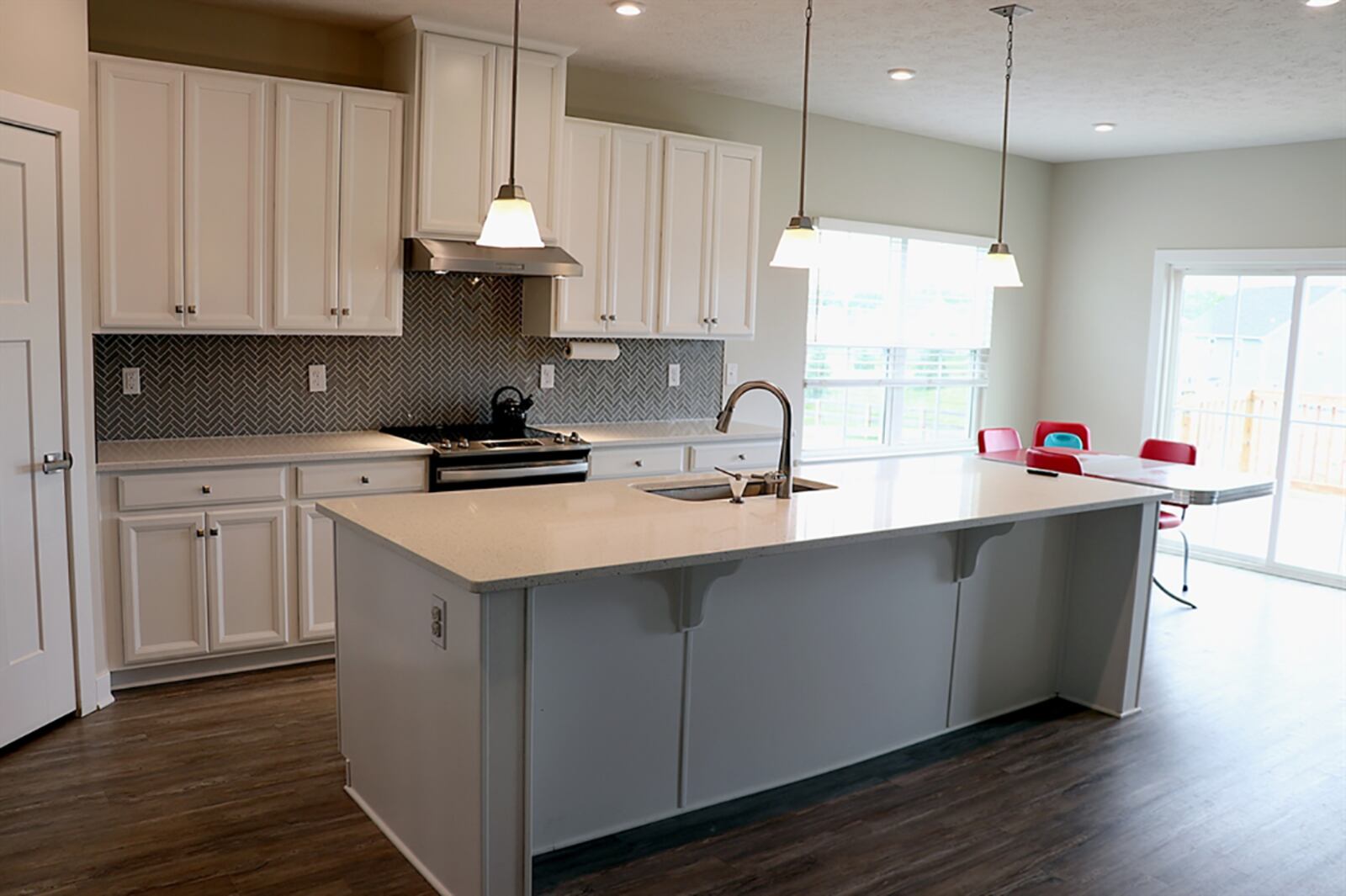 The kitchen has white cabinetry with light countertops and complementing herringbone design ceramic-tile accents the wall space. Tucked into one corner is a walk-in pantry closet with built-in organizers. CONTRIBUTED PHOTO BY KATHY TYLER