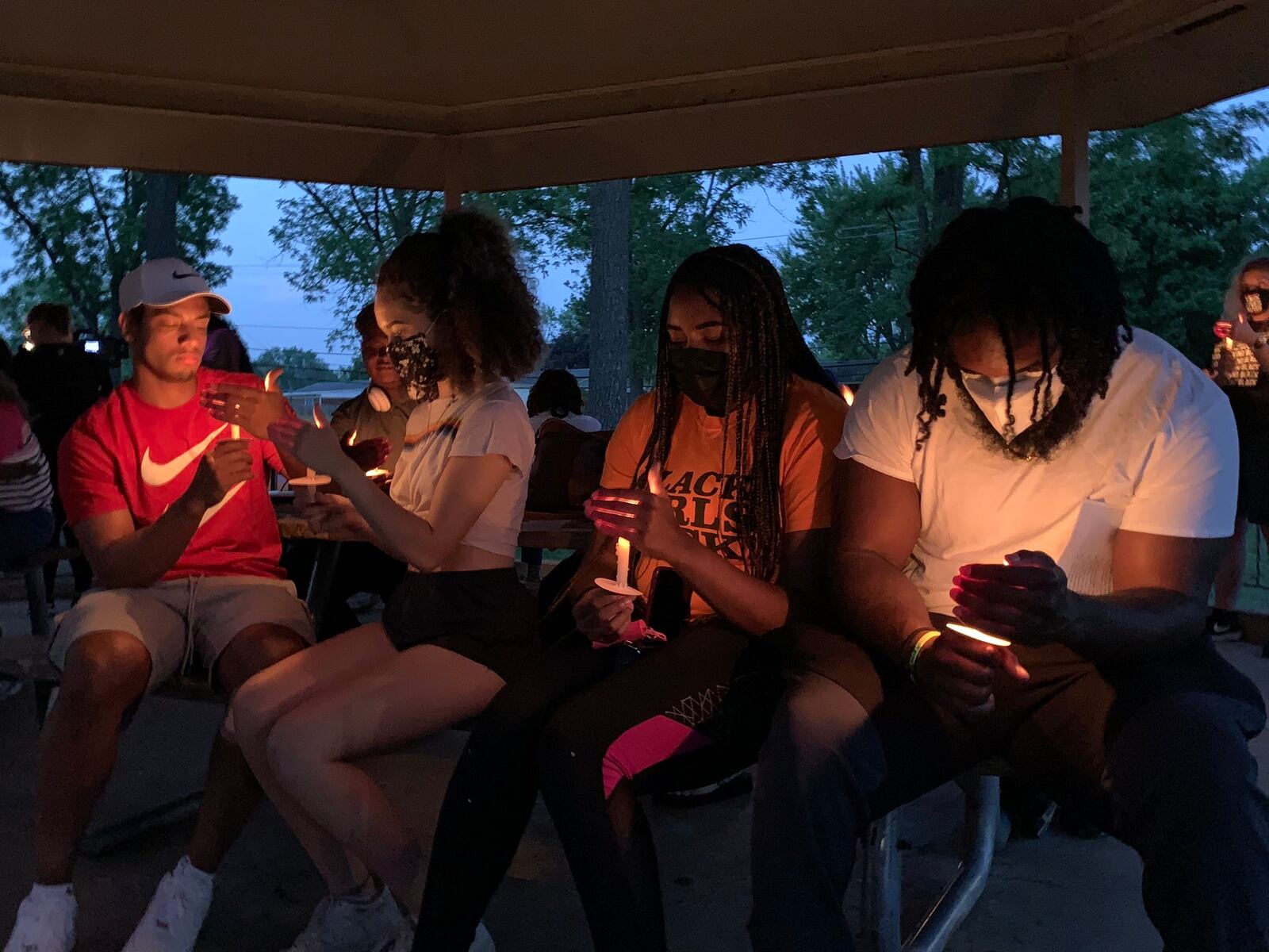 Huber Heights residents hold candles at a vigil on the anniversary of George Floyd's death while a speaker reads the names of Black Americans who have lost their lives at the hands of law enforcement.