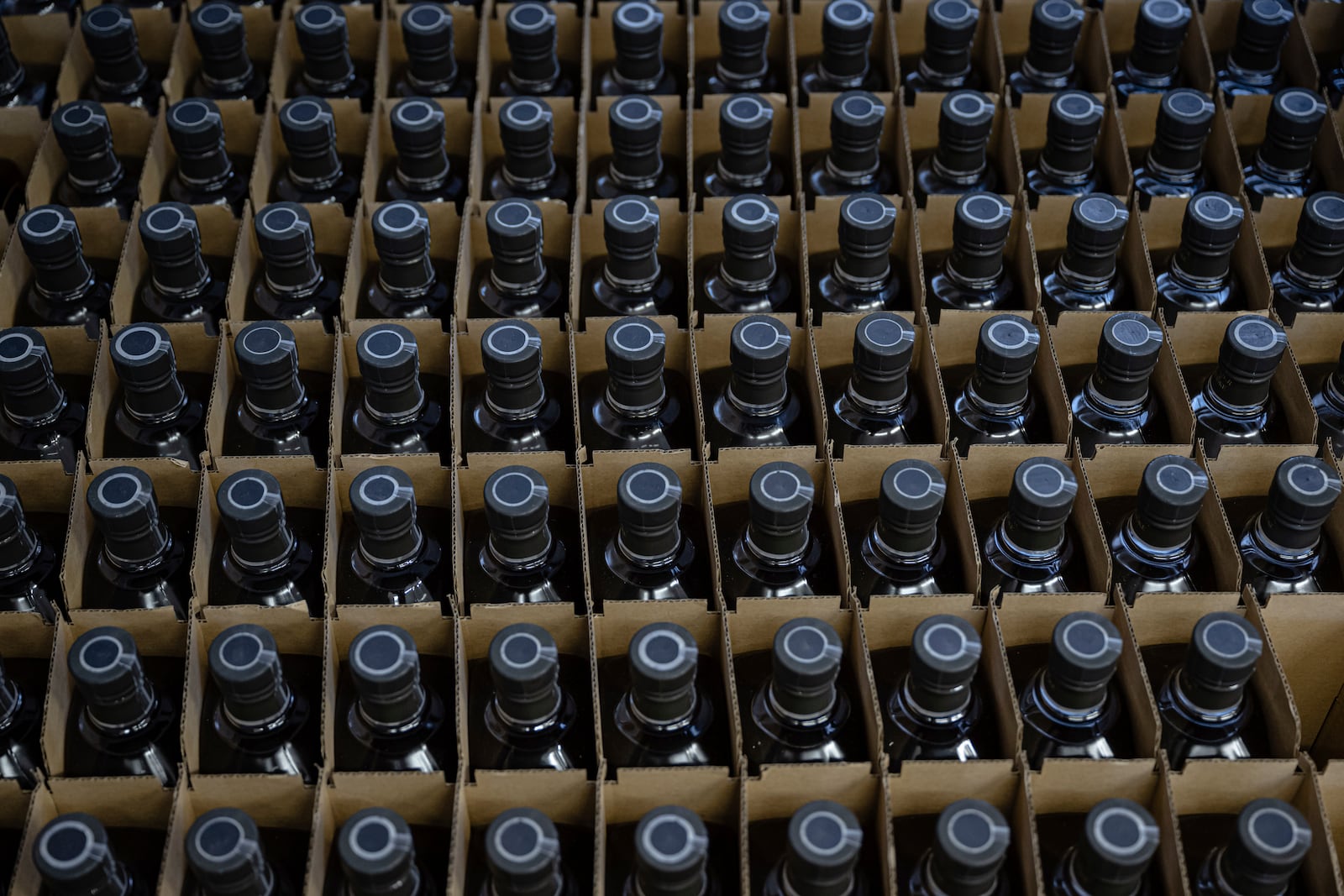 Bottles of product are stored in crates in the bottling area of The Bard Distillery in Graham, Ky., Sunday, March 9, 2025. (AP Photo/Jon Cherry)