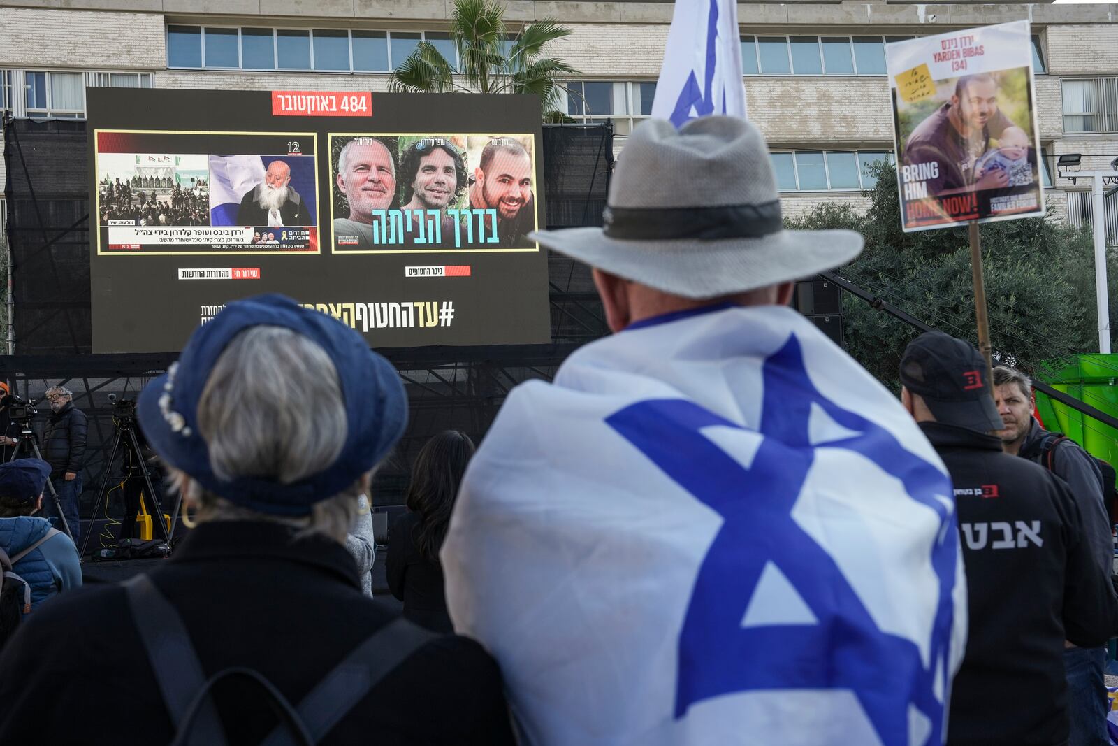 Israelis watch a broadcast of the release of Israelis Ofer Kalderon, 53, and Yarden Bibas, 34, and American-Israeli Keith Siegel, 65 set to be released as part of a ceasefire in the Gaza Strip, in Tel Aviv, Israel, Saturday Feb. 1, 2025. (AP Photo/Oded Balilty)