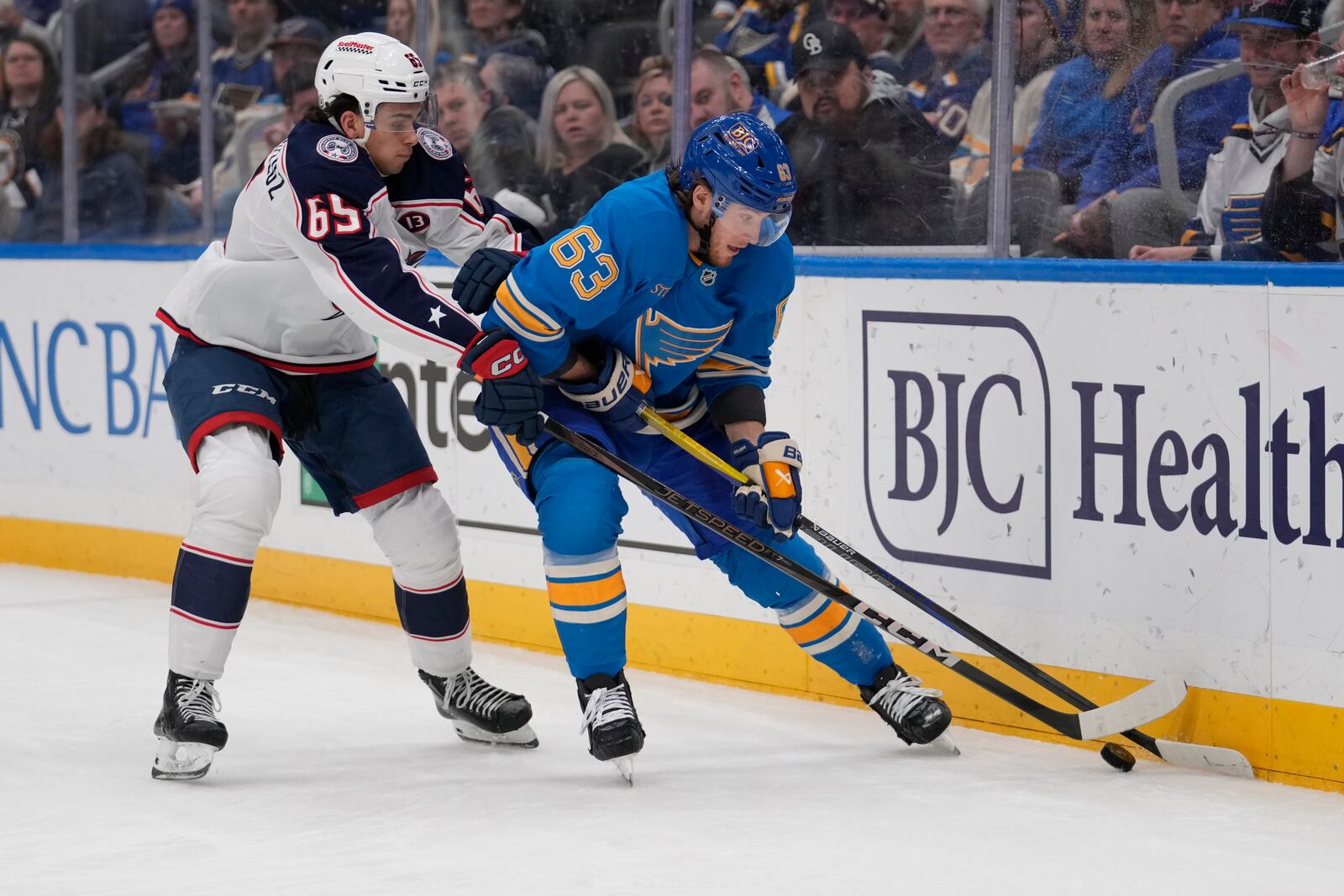 Columbus Blue Jackets' Luca Del Bel Belluz (65) and St. Louis Blues' Jake Neighbours (63) chase after a loose puck along the boards during the second period of an NHL hockey game Saturday, Jan. 11, 2025, in St. Louis. (AP Photo/Jeff Roberson)