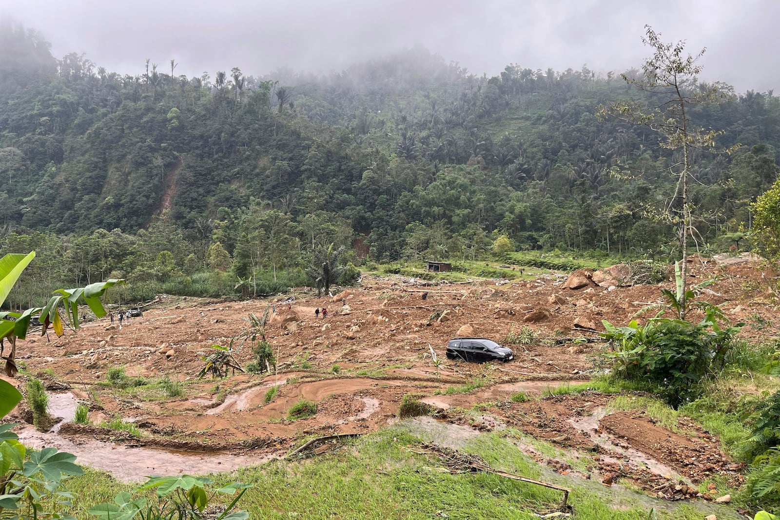 The wreckage of a car is stuck in the mud at an area affected by a landslide following a flash flood in Pekalongan, Central Java, Indonesia, Wednesday, Jan. 22, 2025. (AP Photo/Janaki DM)